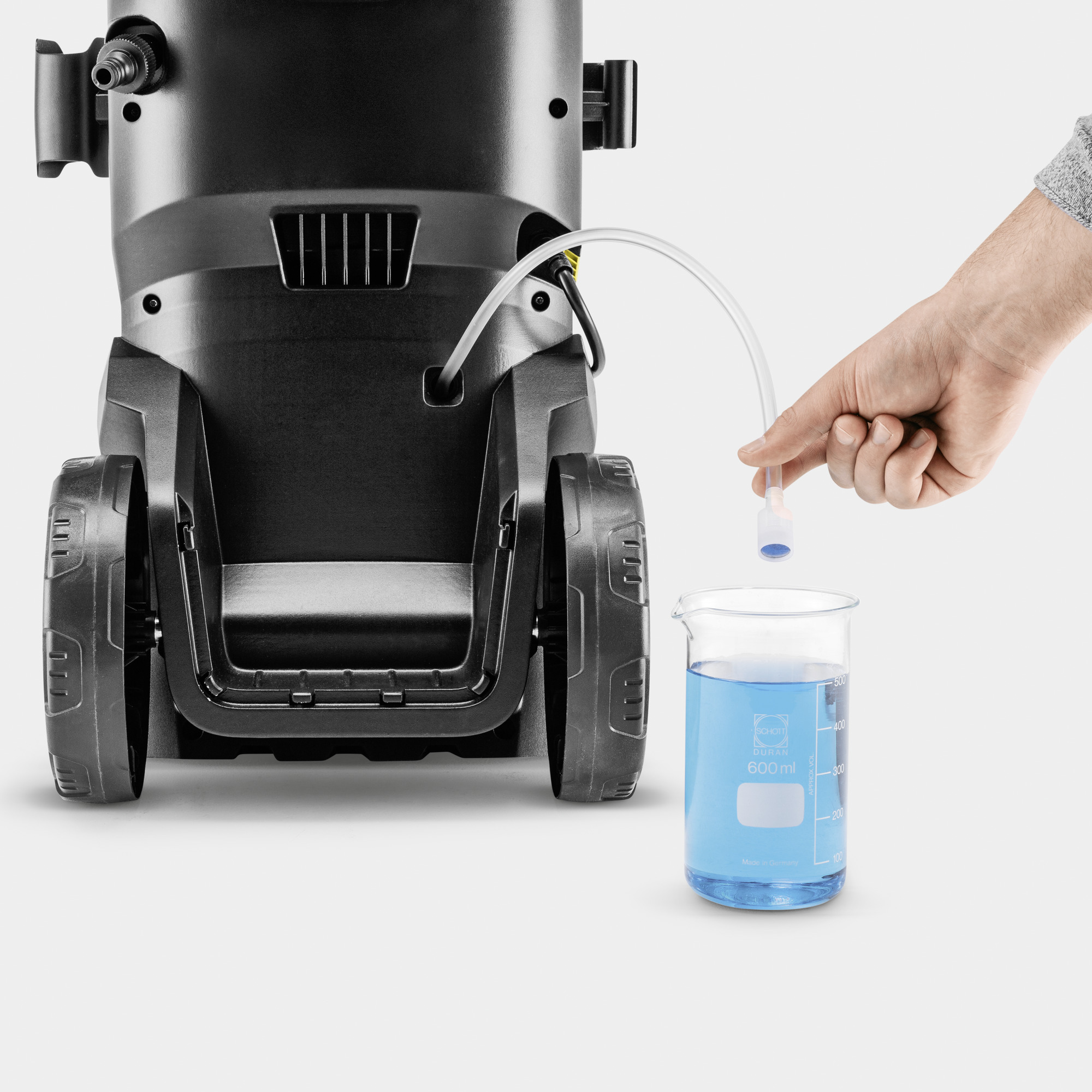 Ręka trzymająca rurkę prowadzącą do zlewki z niebieską wodą.