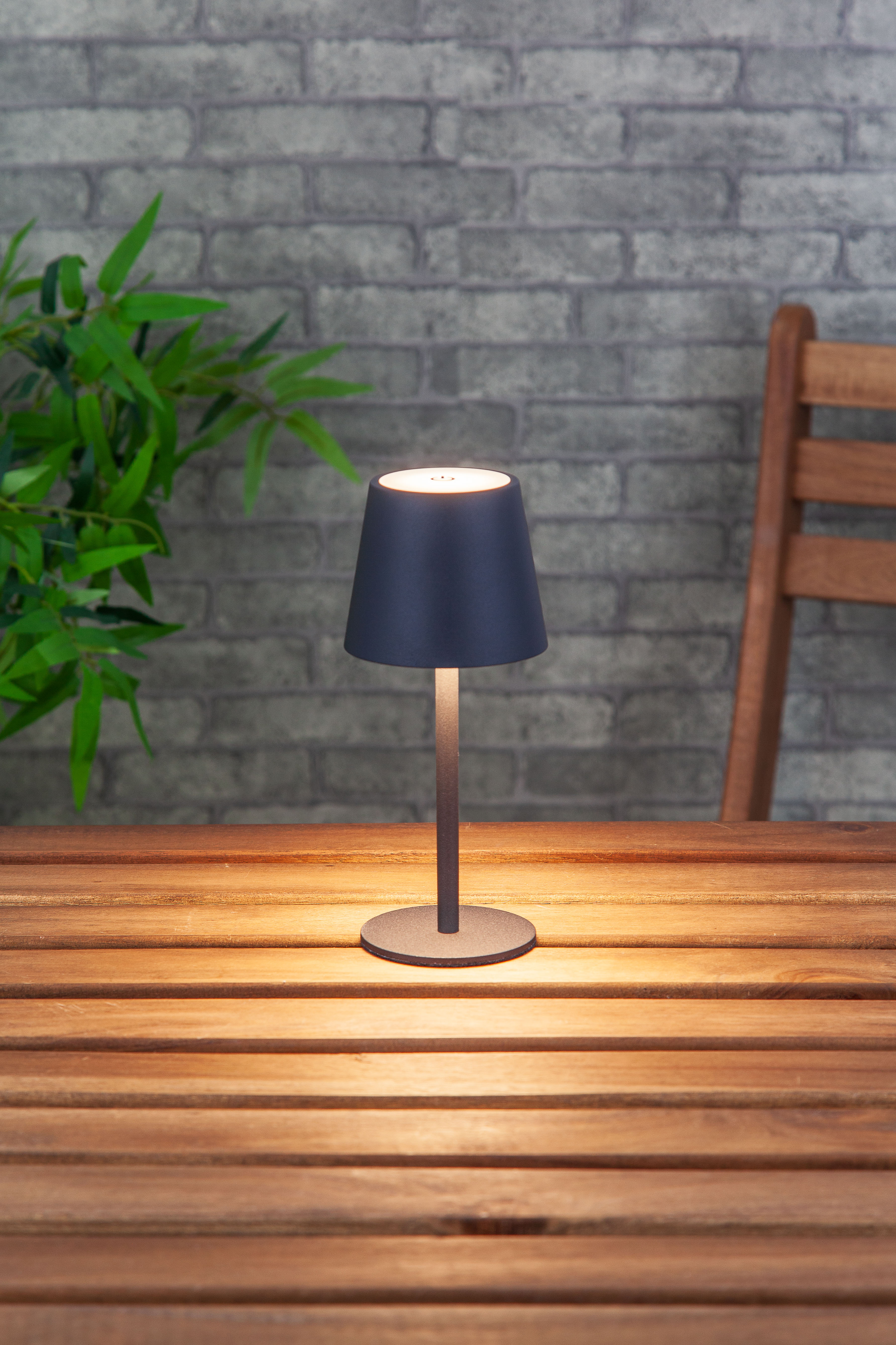Une lampe de table noire avec une base ronde, une tige élancée et un abat-jour conique.
