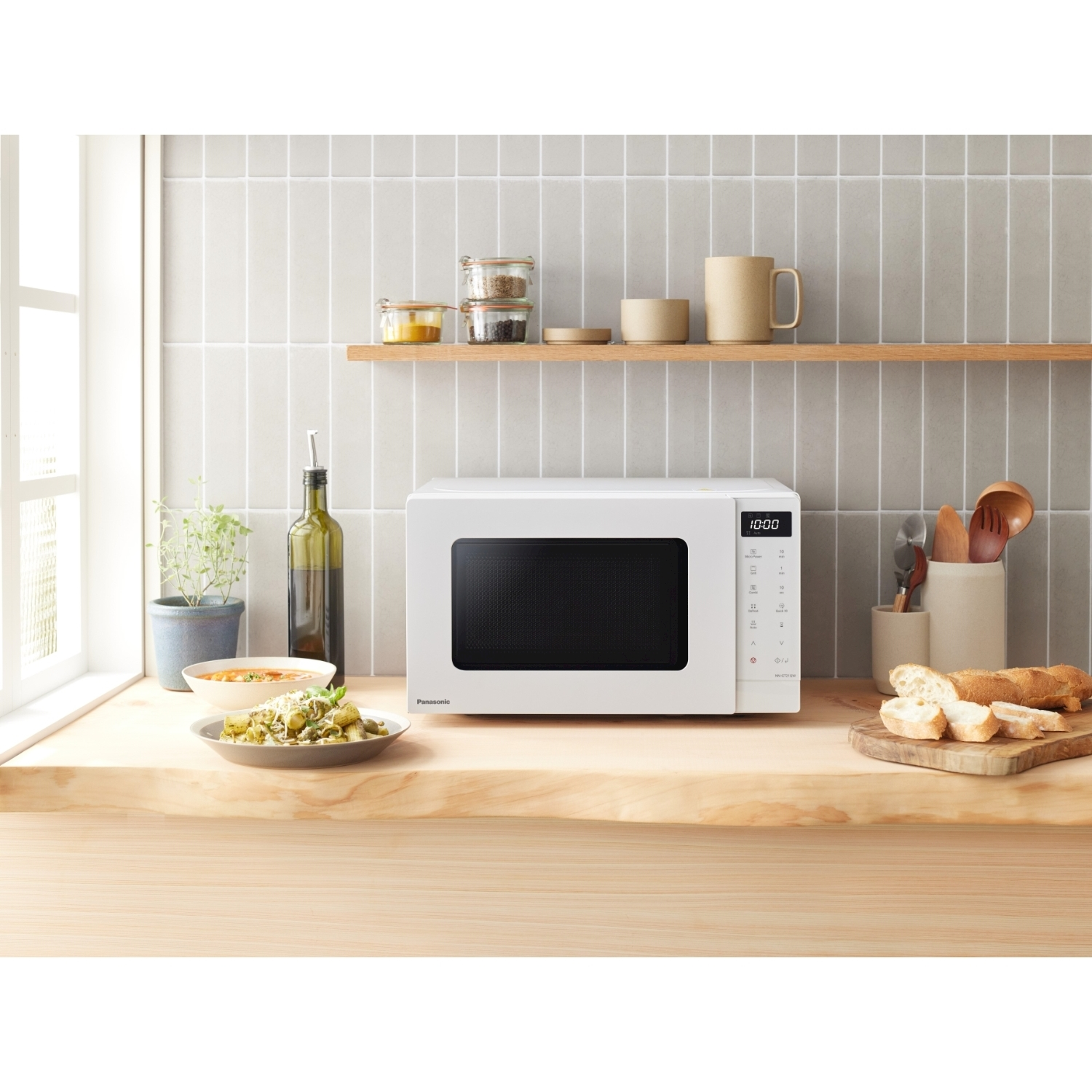 Un forno a microonde bianco su una superficie di legno con cibo e utensili da cucina.