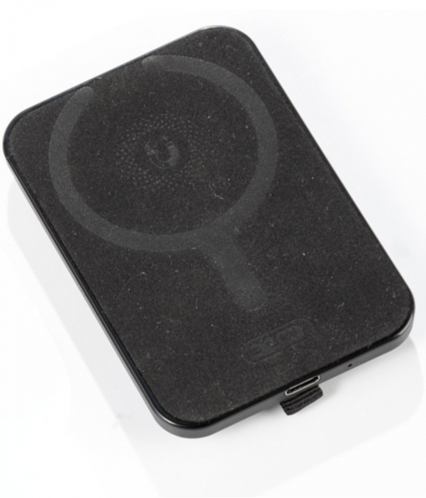 Egy fekete, téglalap alakú töltő kör alakú mintával. USB portja van, és laposan fekszik.