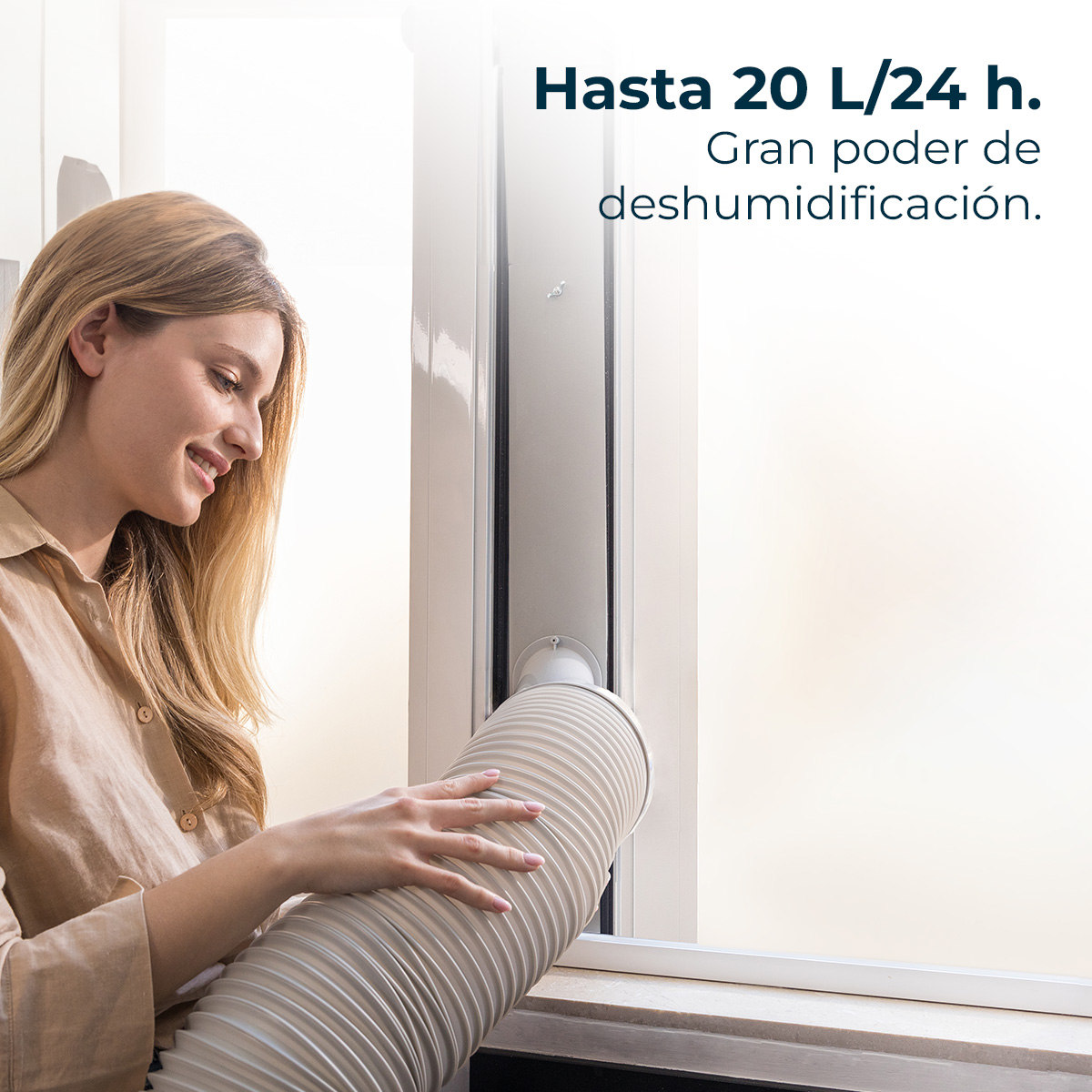 Una mujer sostiene una manguera frente a una ventana. La escritura dice: Hasta 20 L/24 h. Gran poder de deshumidificación.