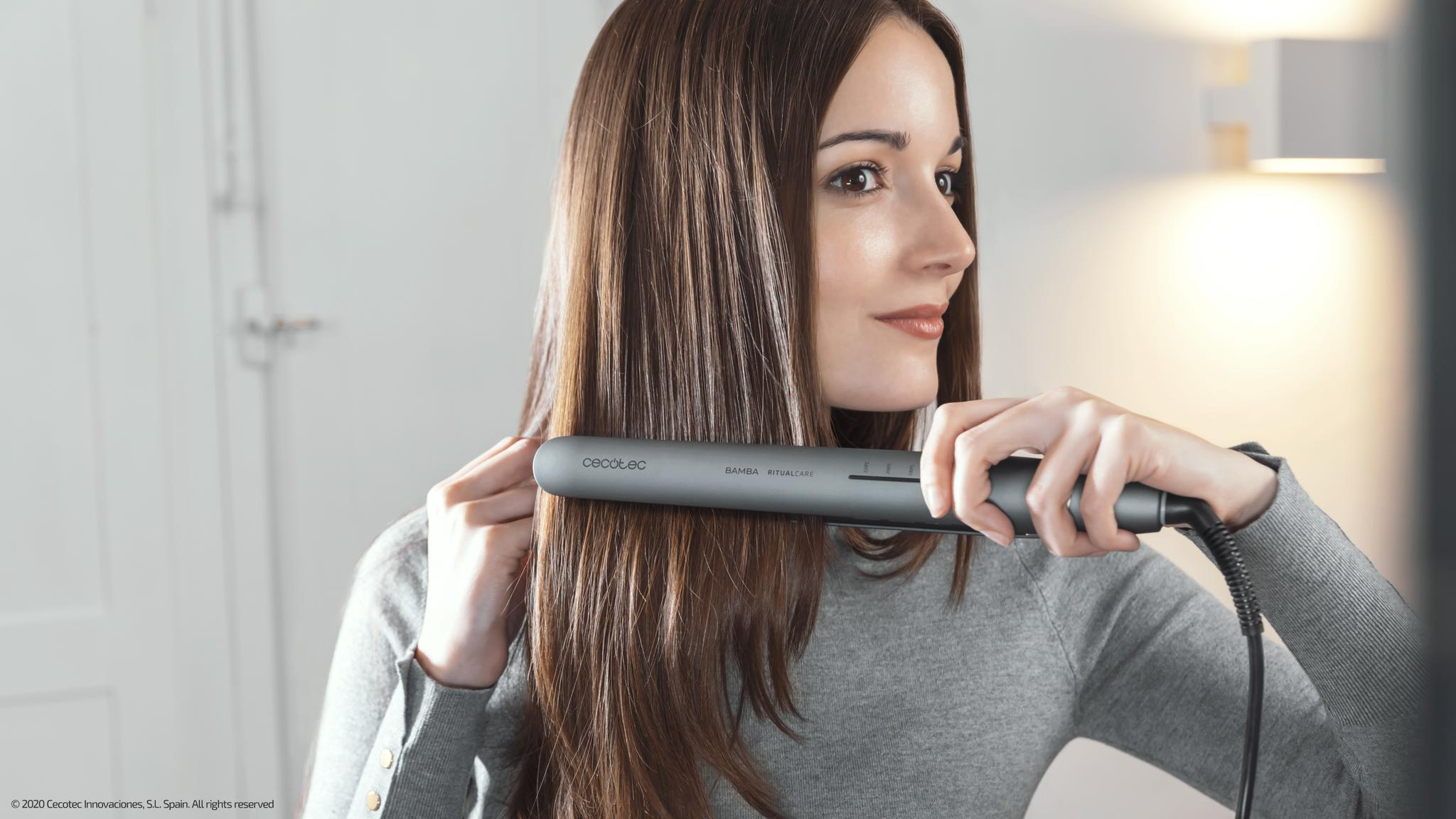 Kobieta prostuje włosy szarą prostownicą. Napis głosi: Cecotec, Bamba RitualCare.