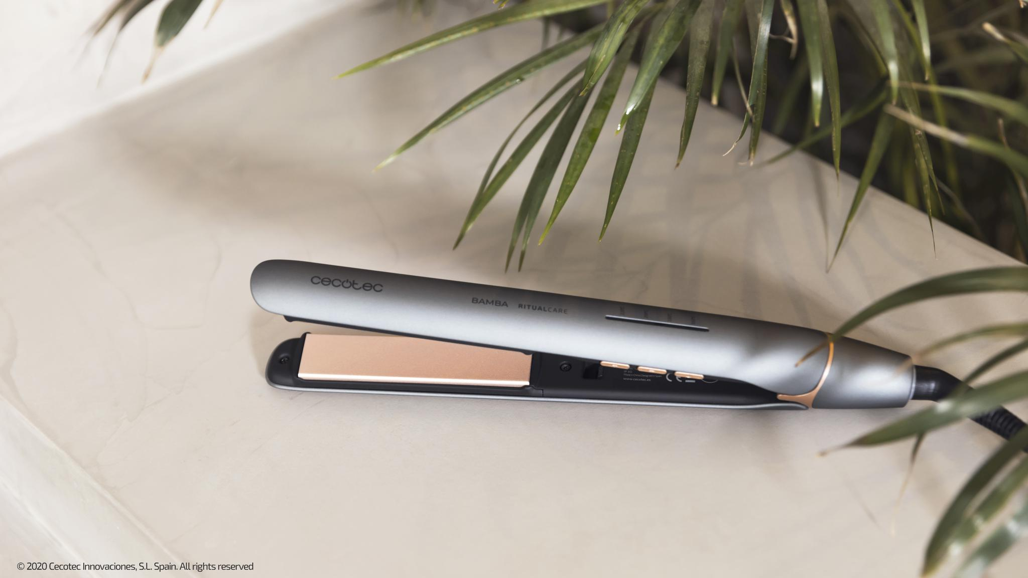 Szara prostownica do włosów leży na białej powierzchni. Napis głosi: Cecotec, Bamba RitualCare.