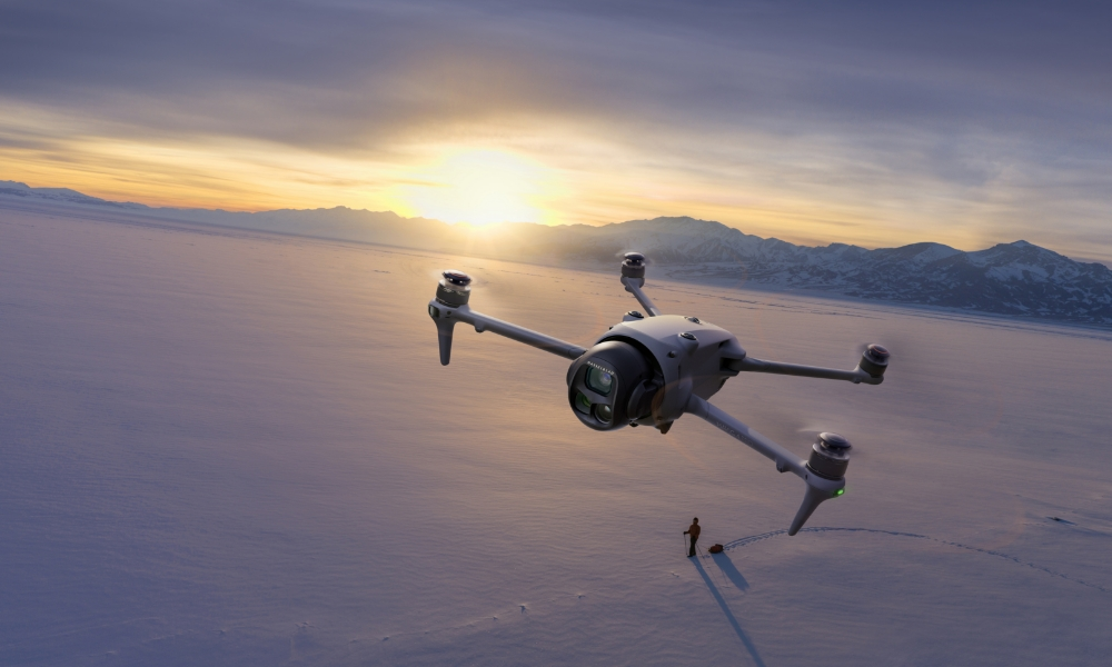 Dron lecący nad zaśnieżonym polem o zachodzie słońca, osoba idąca.