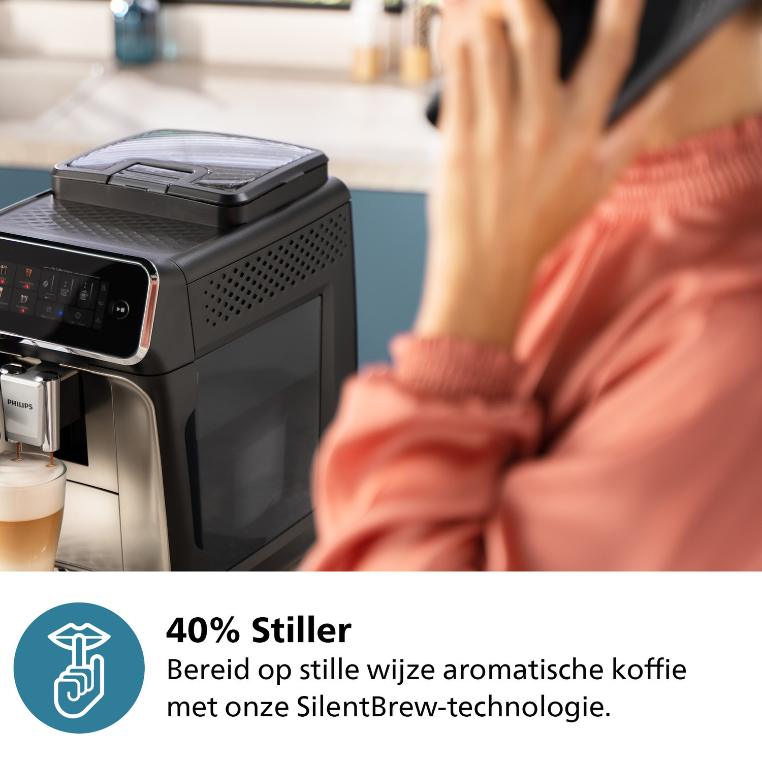 Persoon aan de telefoon naast een koffiemachine, met tekst over 40% stillere koffiebereiding.