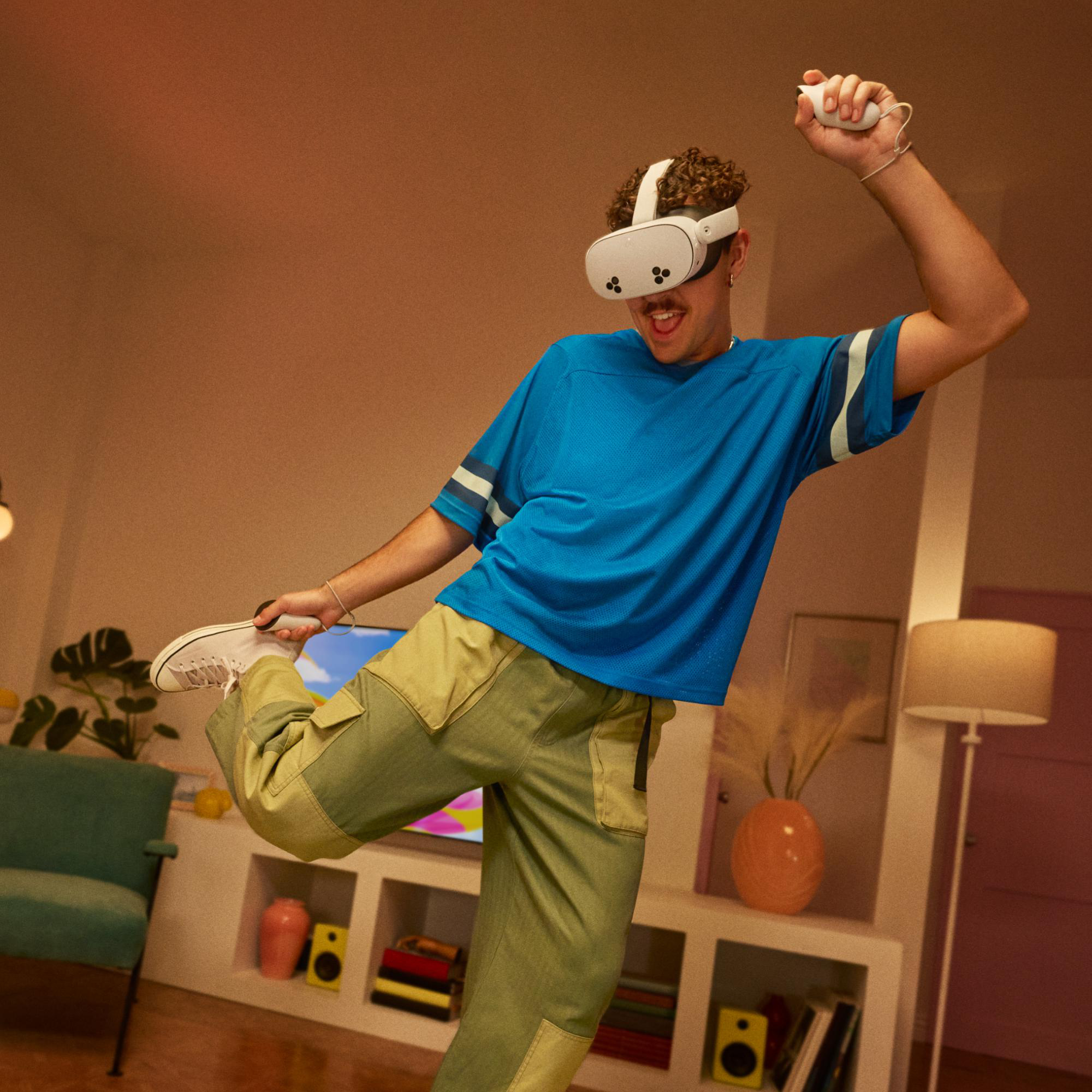 Ein Mann in blauem T-Shirt und grüner Hose mit VR-Brille, der in einem Wohnzimmer tanzt.