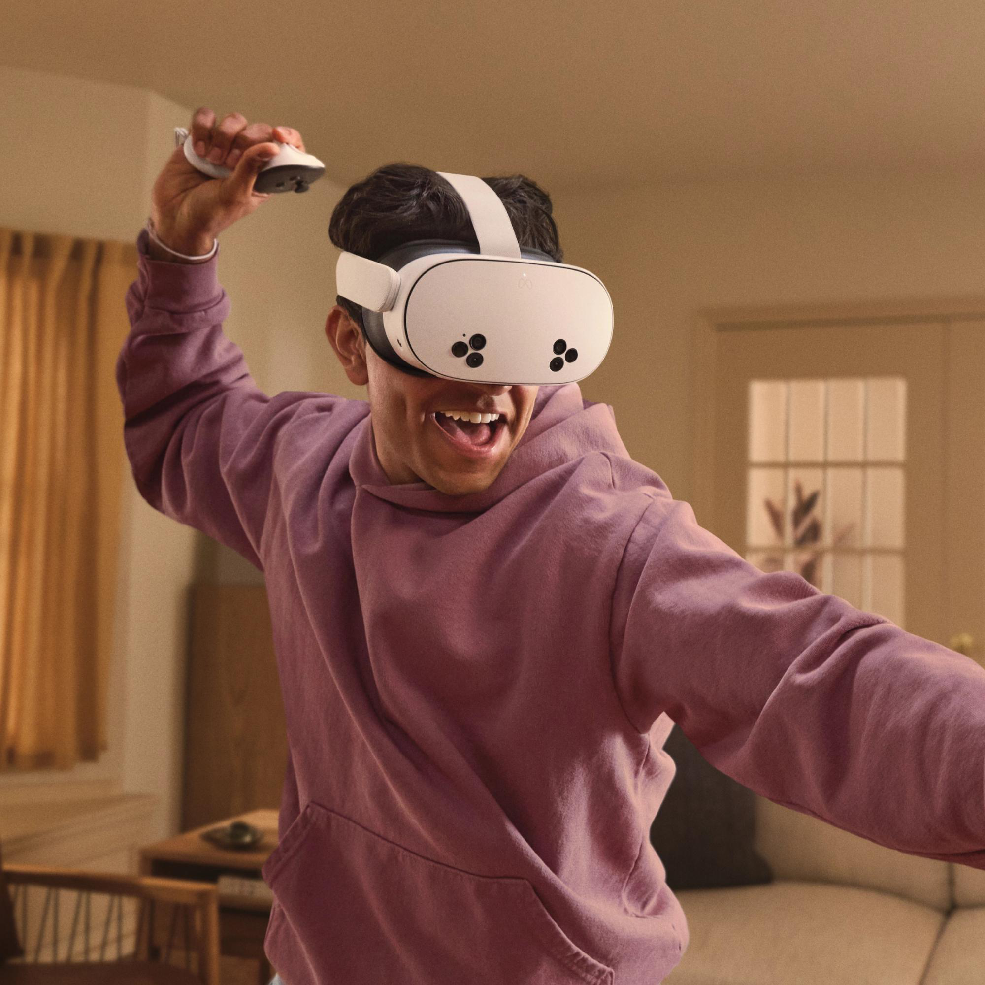 Ein Mann mit VR-Brille und Controllern, lächelnd, in einem Raum. Er scheint Spaß zu haben.