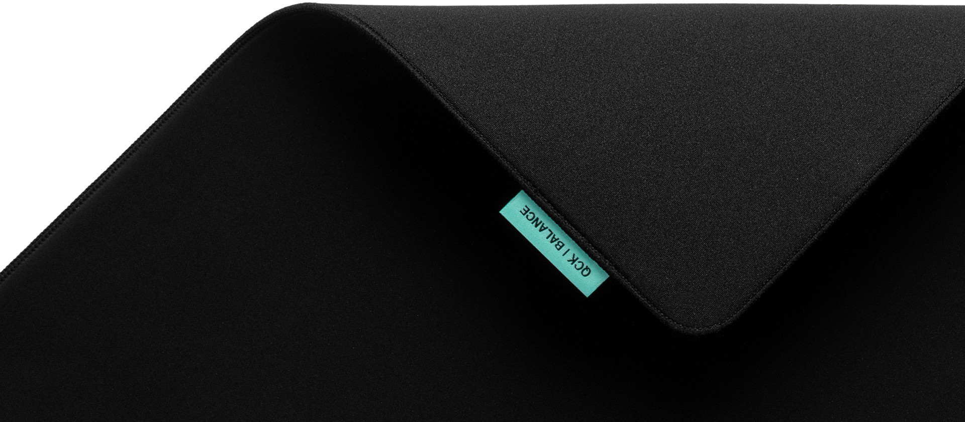 Zbliżenie czarnej podkładki pod mysz z niebieską etykietą GCK/BALANCE.