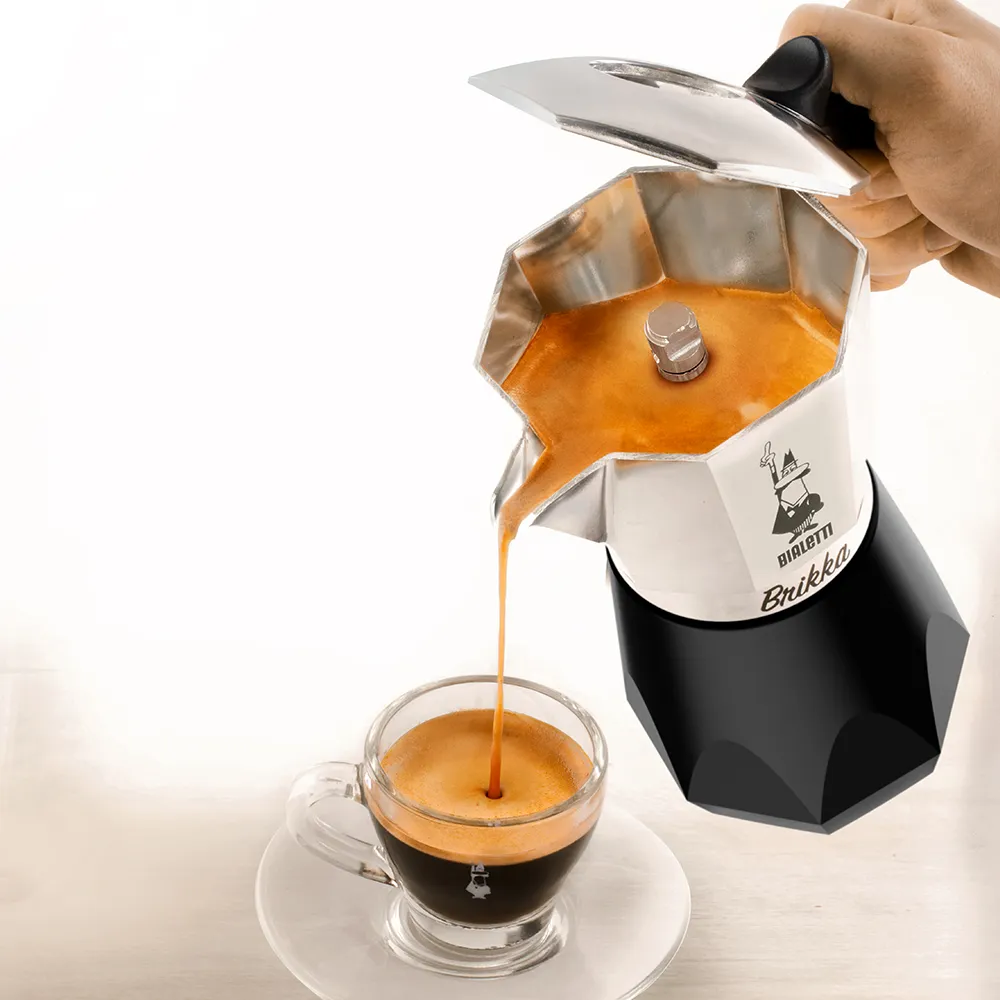 Eszpresszó ömlik egy pohárba. Az eszpresszó készítő látható. A "Bialetti Brikka" név látható.