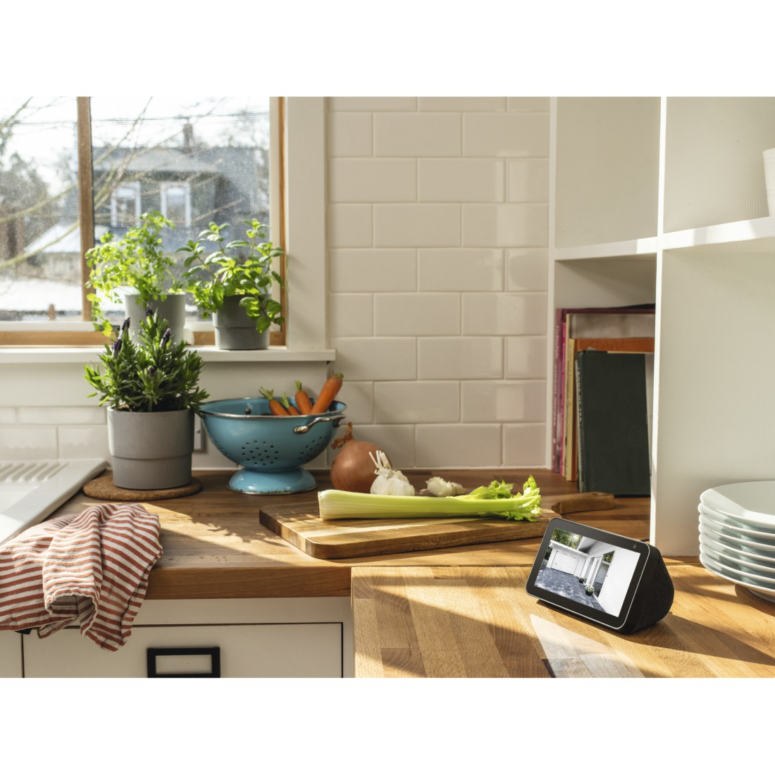 Eine Küche mit Pflanzen, Gemüse und einem Tablet mit einem Garagenbildschirm. Ein Fenster ist im Hintergrund.