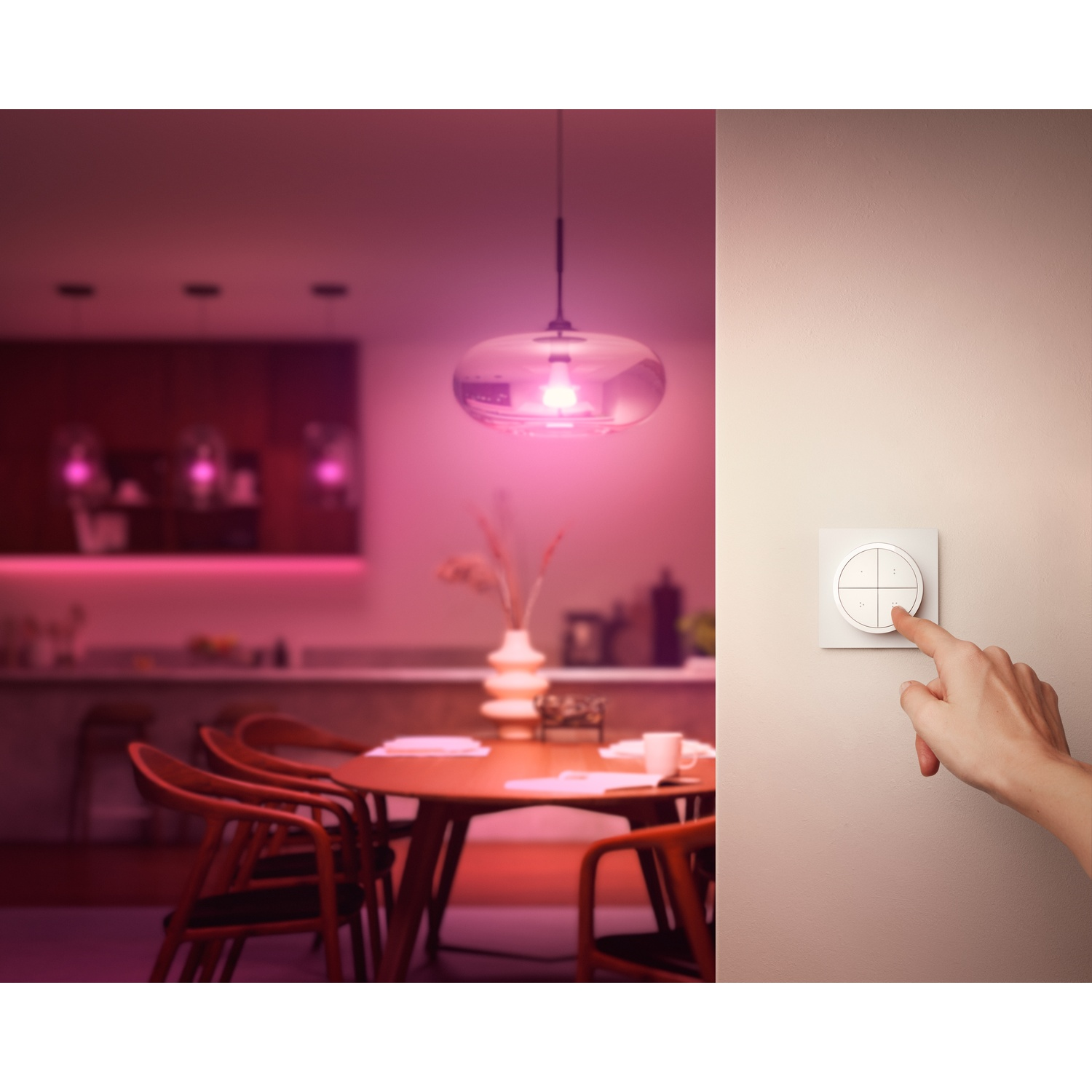 Una mano tocca un interruttore Philips Hue bianco sul muro mentre una stanza è illuminata con luce colorata.