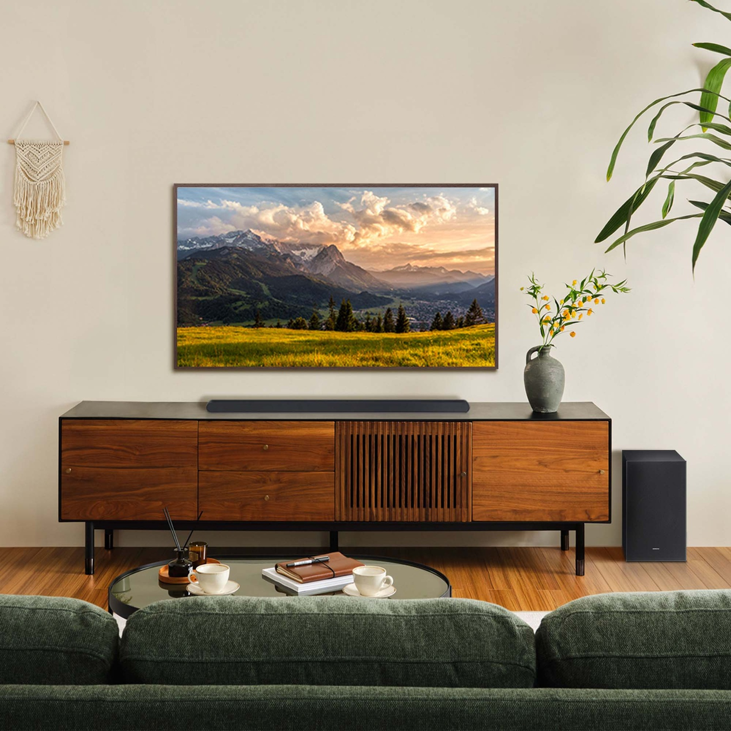Soggiorno con TV, soundbar e subwoofer. Montagne in TV. Divano, tavolo con caffè e decorazioni.