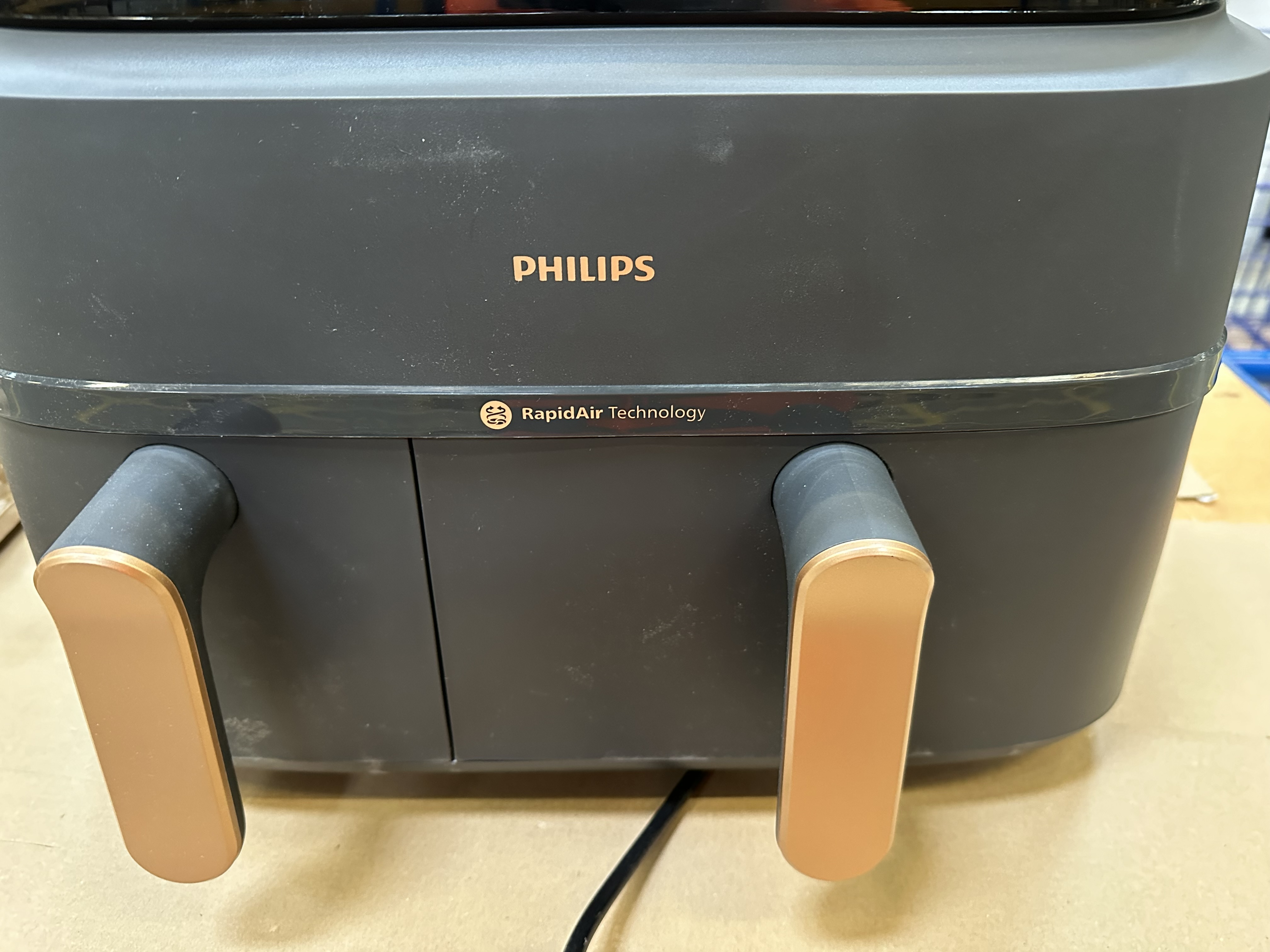 Zbliżenie czarnej frytkownicy Philips ze złotymi uchwytami i logo, technologia Rapid Air.