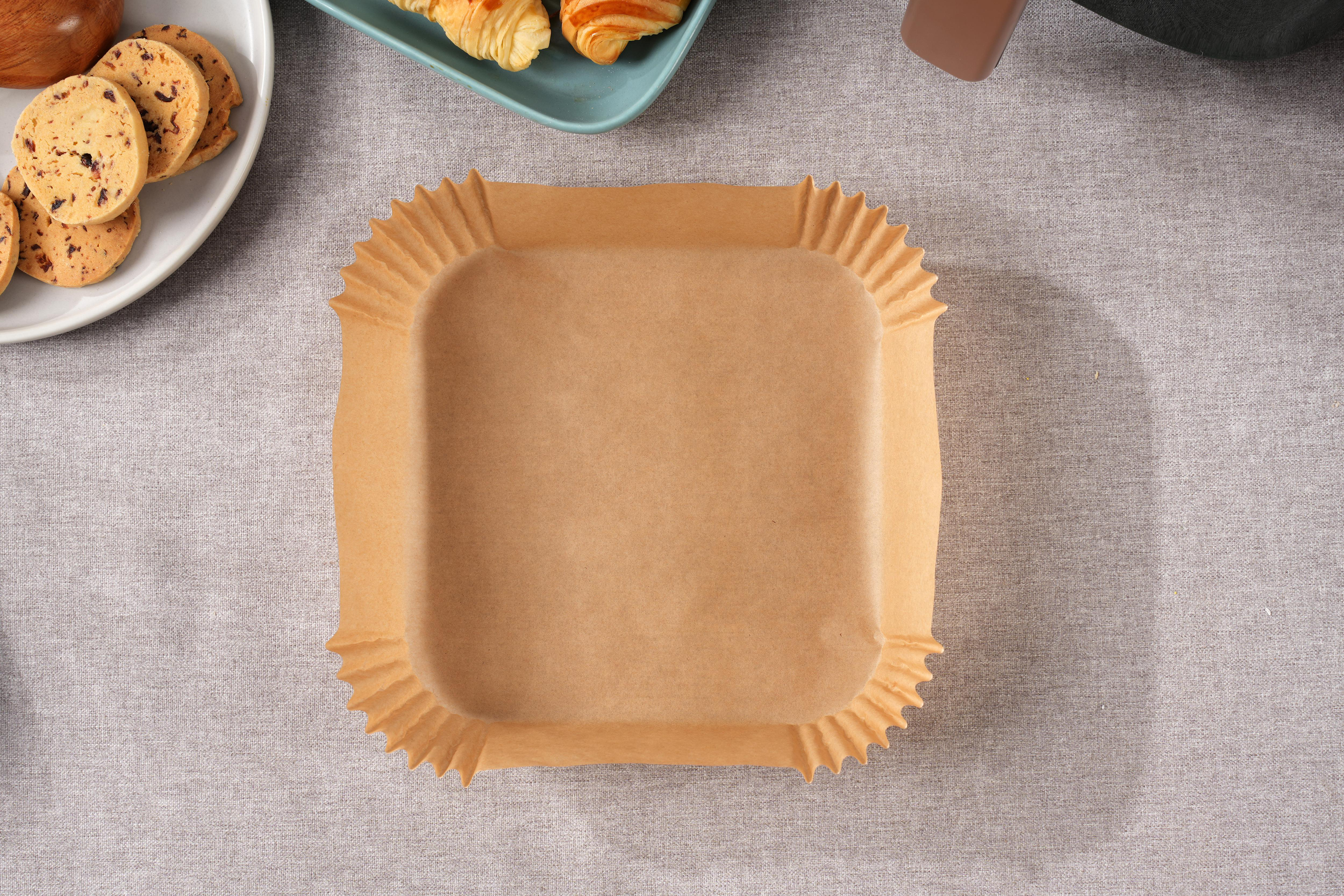 Croissants mit Sesam auf braunen Papierbackformen auf einem grauen Tisch, daneben Kekse.
