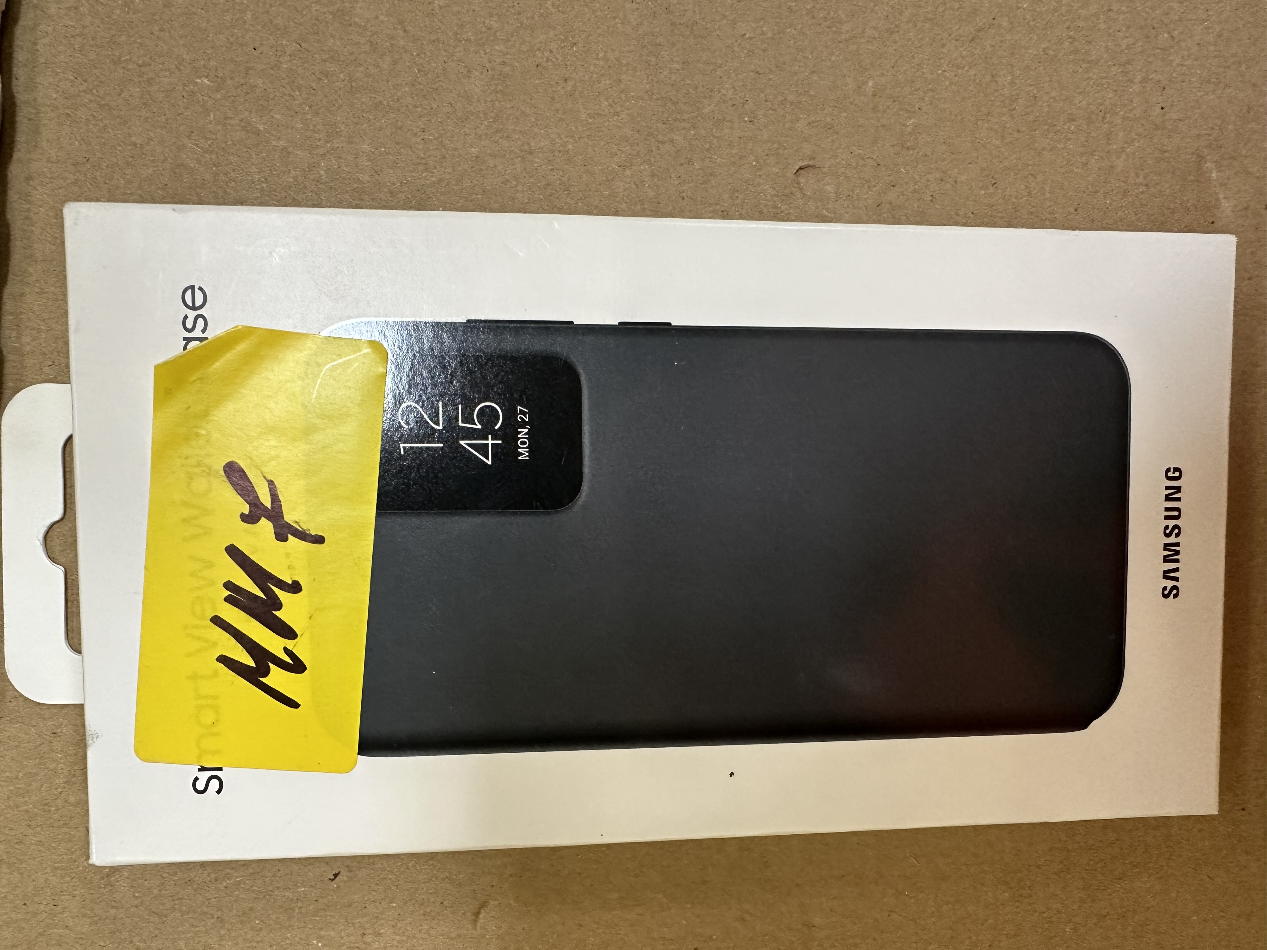 Czarne etui na telefon w białym pudełku z żółtą naklejką "MM 7".