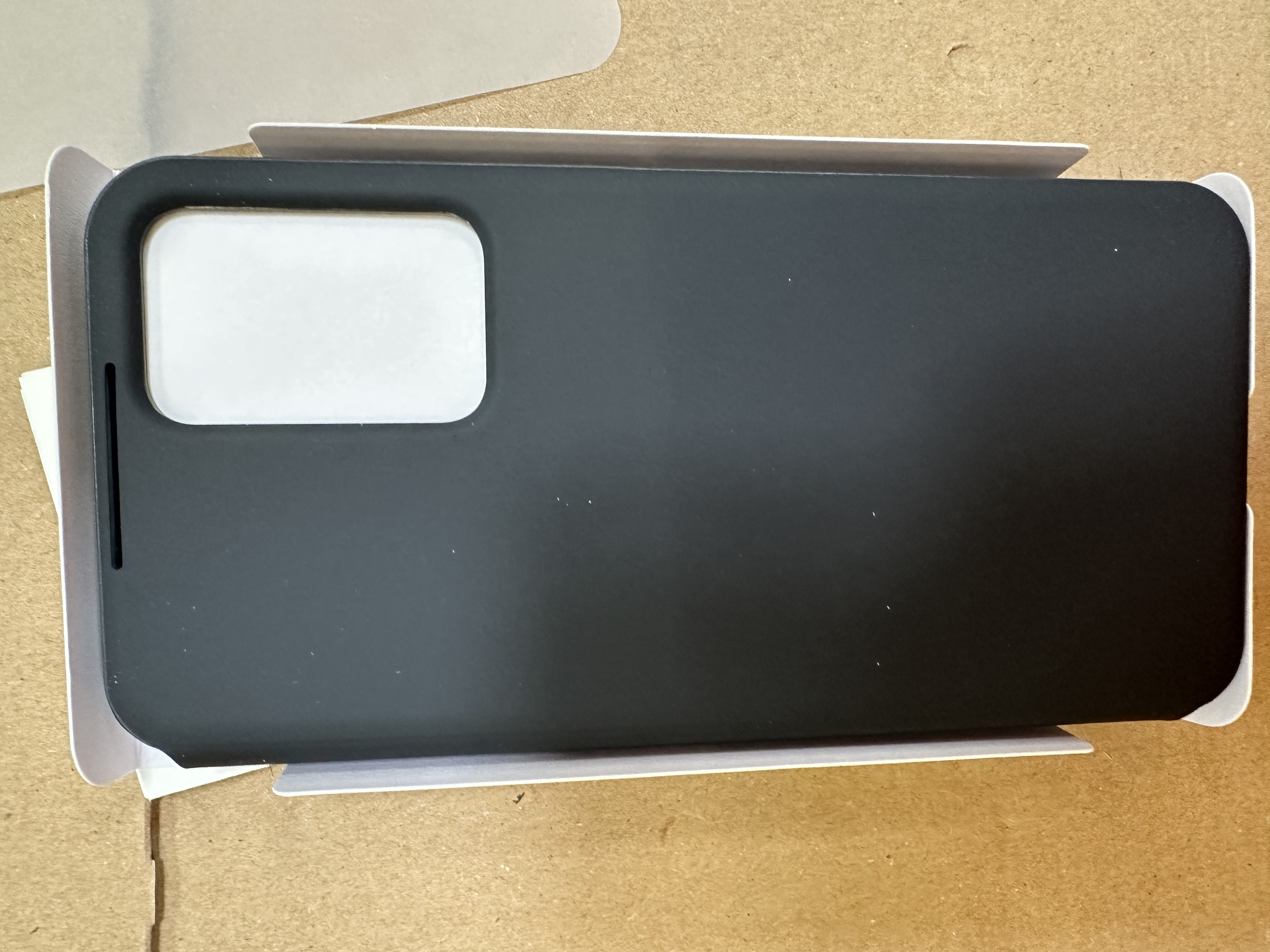 Czarne etui na telefon w białym pudełku, z białym wycięciem na aparat.