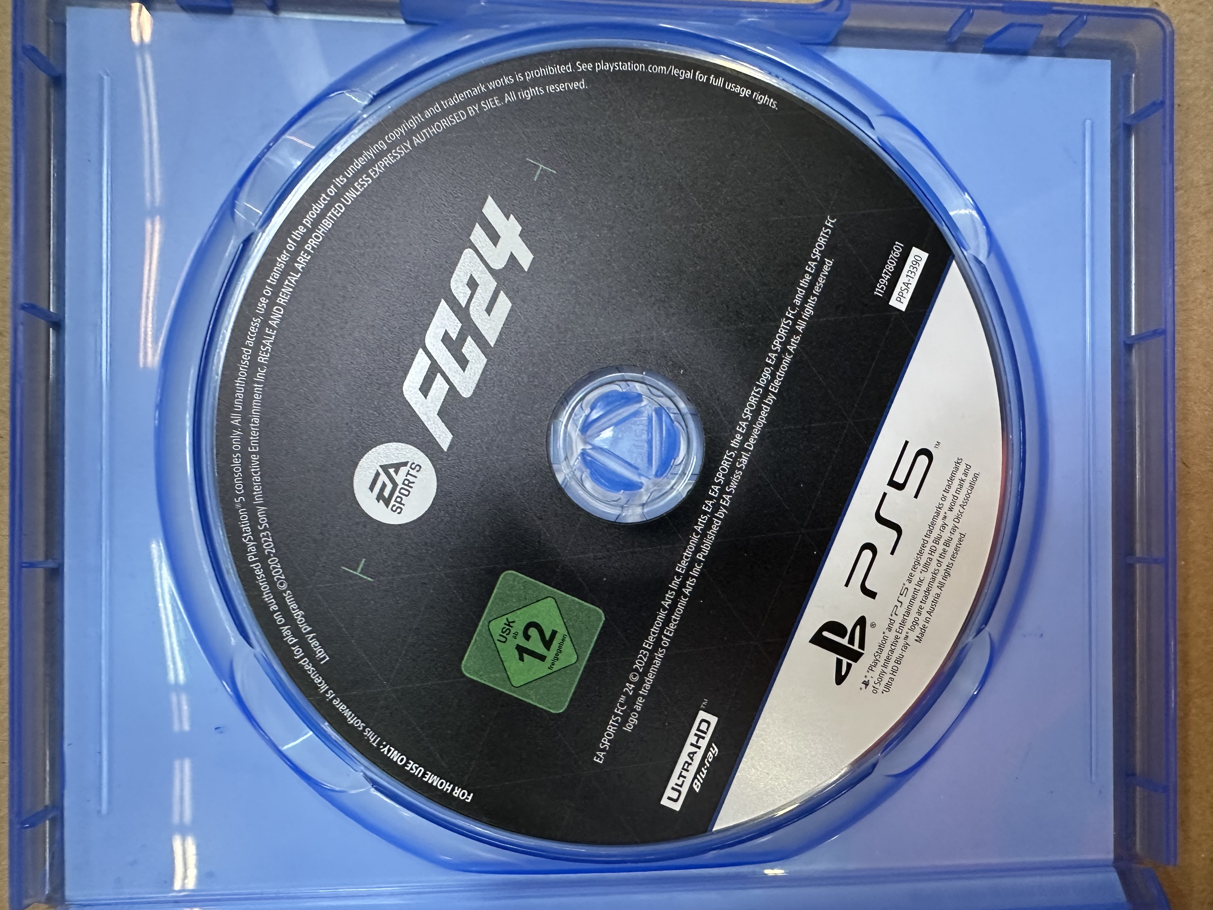 Płyta z grą wideo z napisem FC24. Logo PS5 i klasyfikacja wiekowa. Niebieskie etui.