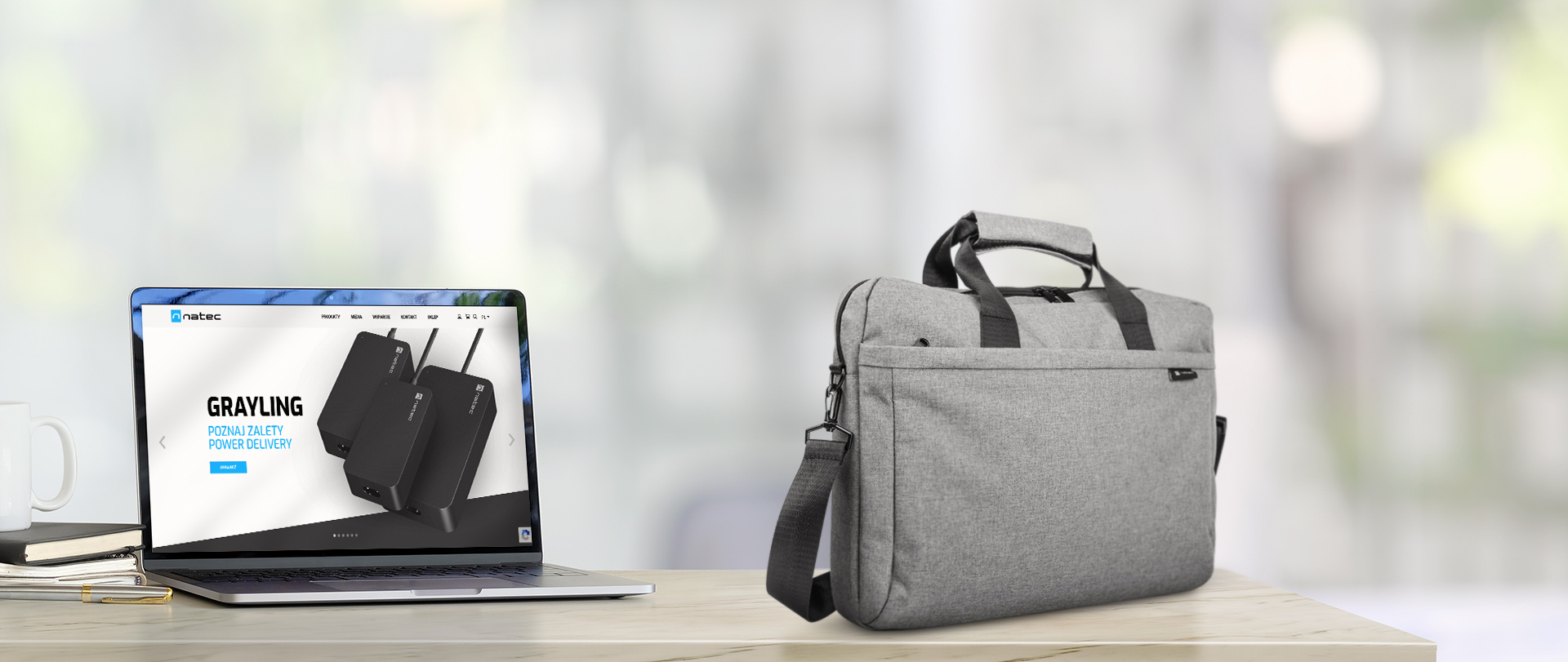 Laptop az asztalon, mellette laptop táska és weboldal képernyőfotó.