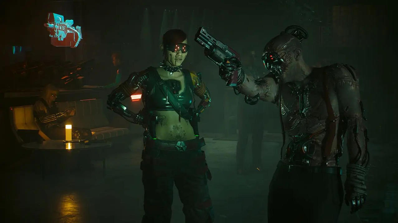 Zwei Cyborgs stehen sich gegenüber, einer hält eine Waffe. Andere im Hintergrund. Rot beleuchteter Raum.