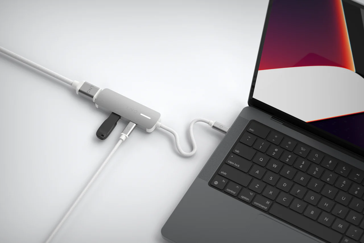 Un portátil conectado a un adaptador multipuerto LINO, con un cable USB-C y otros puertos.