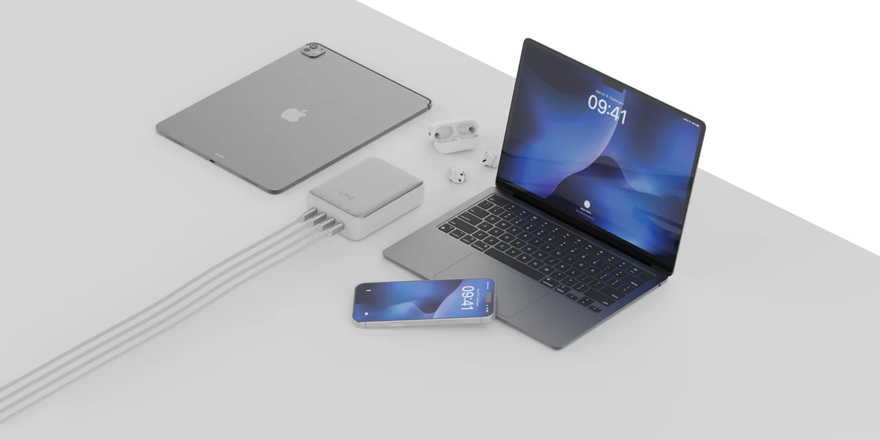 Un iPad, un portátil, un iPhone y unos AirPods están conectados a un concentrador en una superficie blanca.