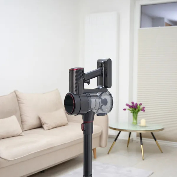 Czarny i czerwony odkurzacz bezprzewodowy stoi w salonie. Beżowa sofa, szklany stolik i kwiaty są w tle.