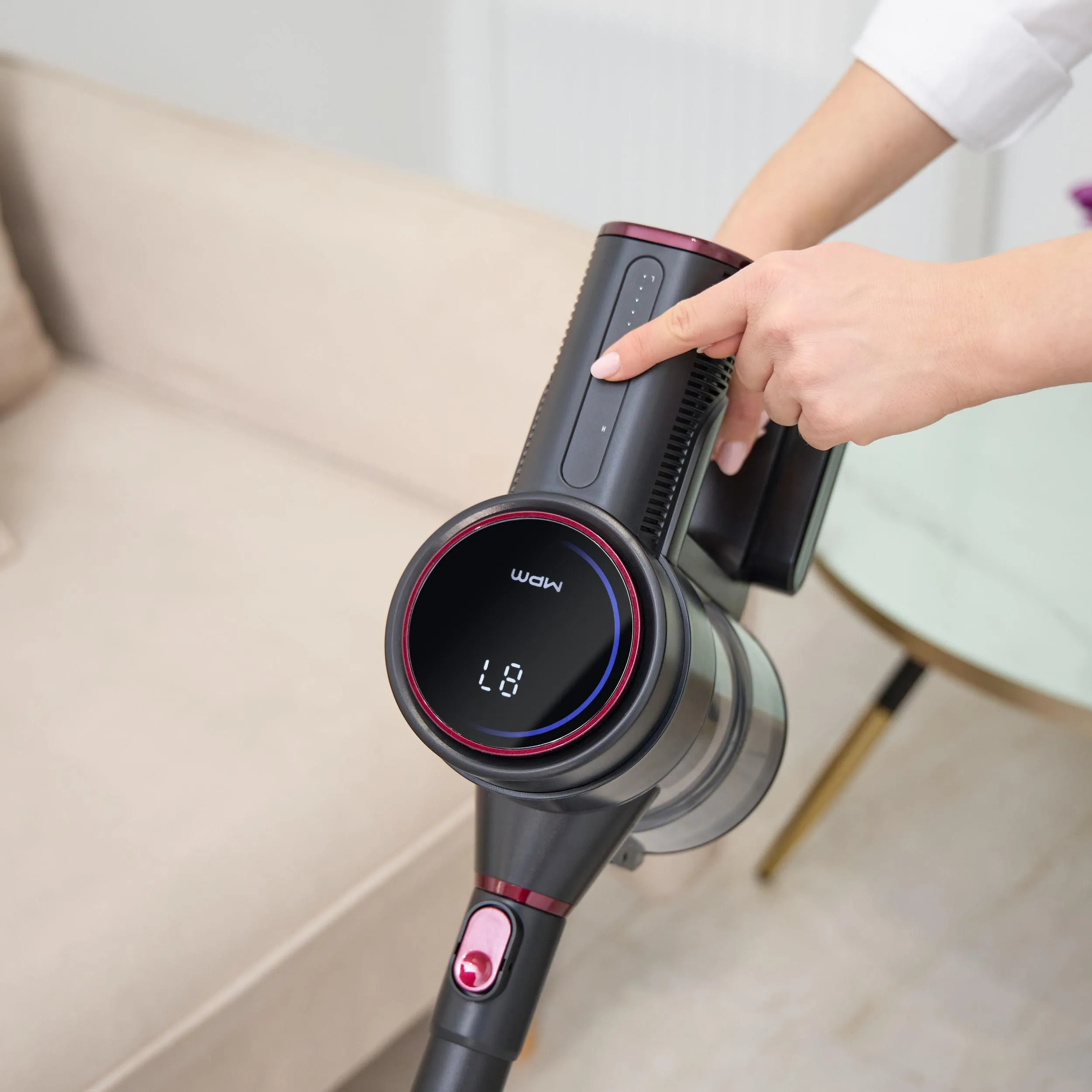 Ręka kobiety włączająca odkurzacz z ekranem.