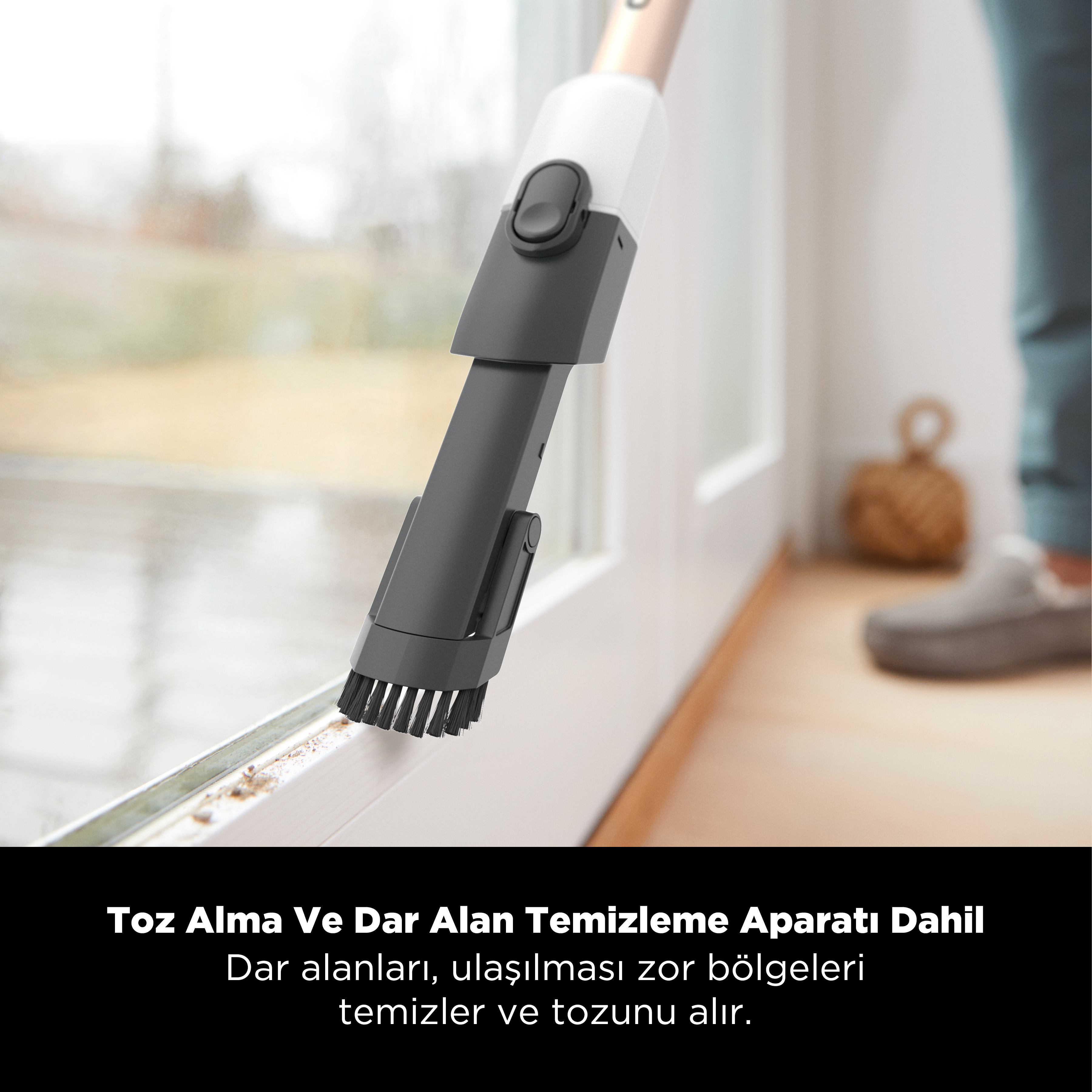 Bir elektrik süpürgesi başlığı bir kapı çerçevesini temizliyor. Fırça siyahtır ve kapı çerçevesi beyazdır. Gri bir kapı.