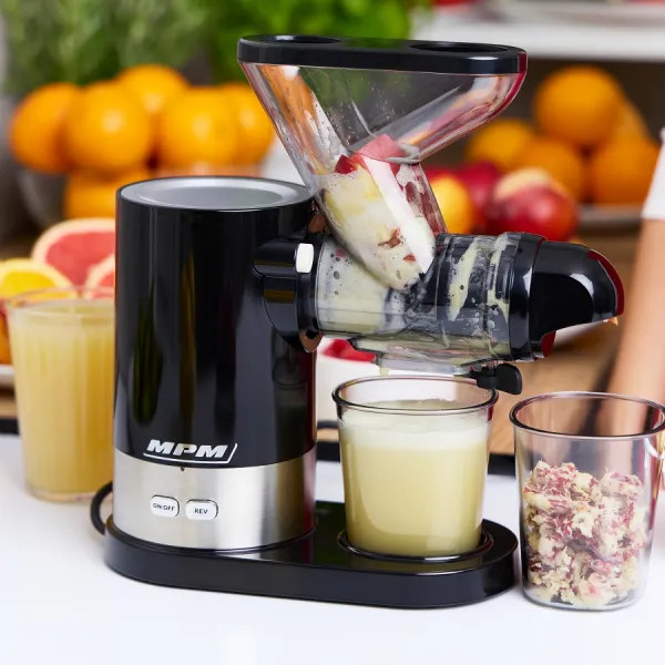 Czarna wyciskarka do soku robi sok, szklanka soku, miąższ i pomarańcze w tle.