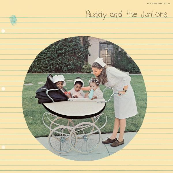 Drei Babys in einem weißen Kinderwagen, eine Krankenschwester betreut sie. Grünes Gras und ein Haus im Hintergrund. Titel "Buddy and the Juniors".