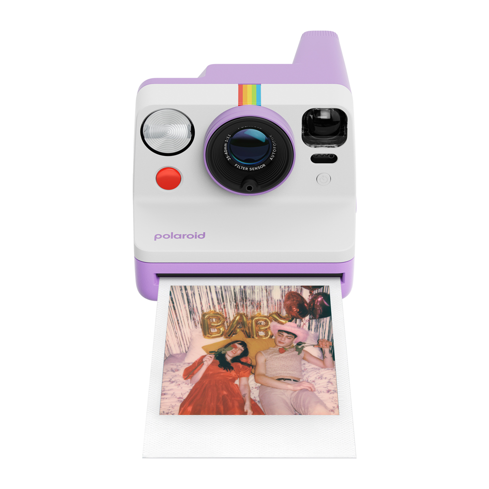 Beyaz ve mor Polaroid kamera, bir çiftin fotoğrafı ve arka planda 'BABY' balonu ile.