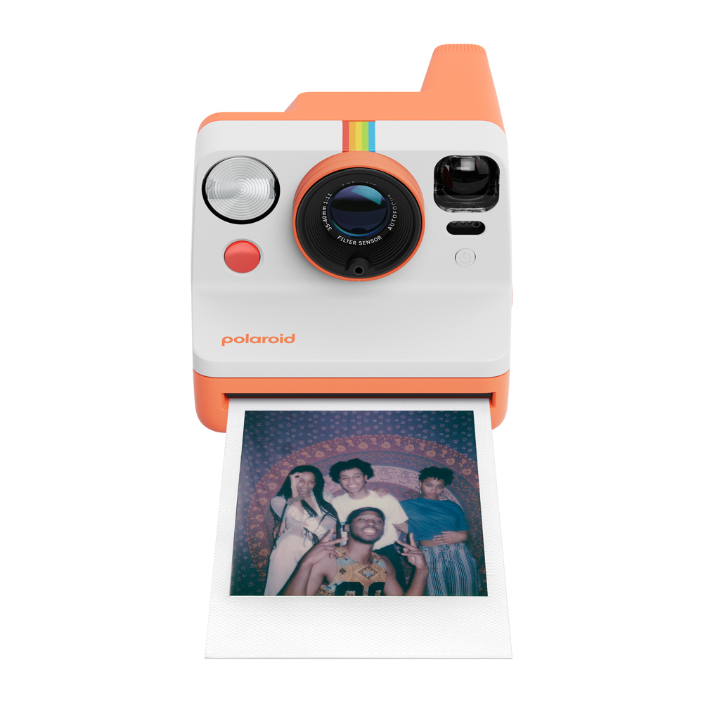 Turuncu ve beyaz Polaroid kamera, beyaz bir yüzey üzerinde insanların fotoğrafını basıyor.