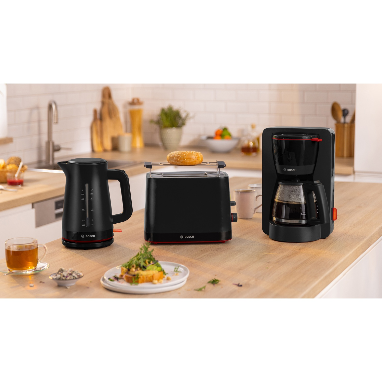 Piano cucina con bollitore, tostapane e macchina da caffè. Cibo su un piatto.