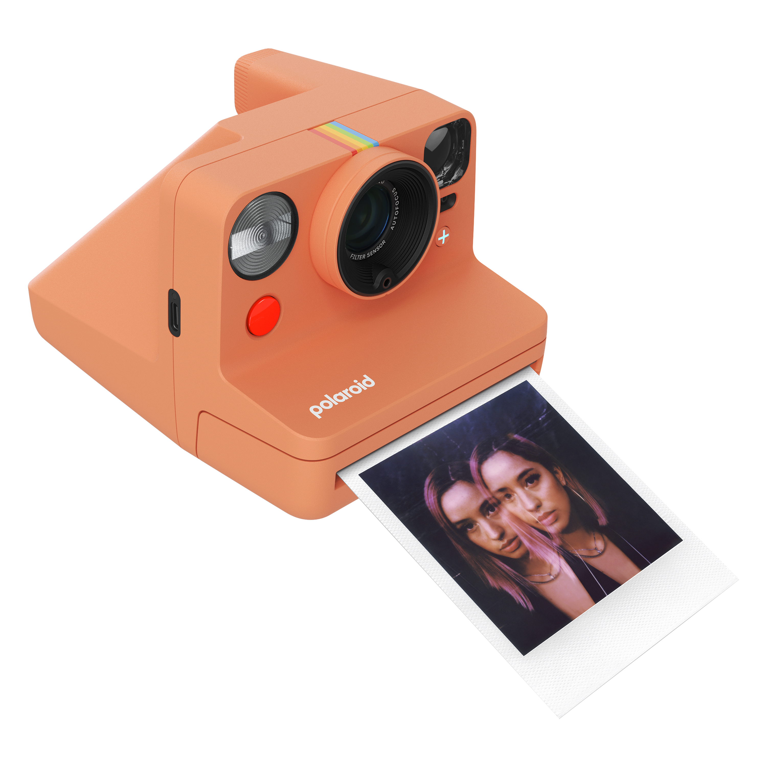 İki kadının fotoğrafının bulunduğu turuncu bir Polaroid kamera. Fotoğraf kameradan çıkıyor.