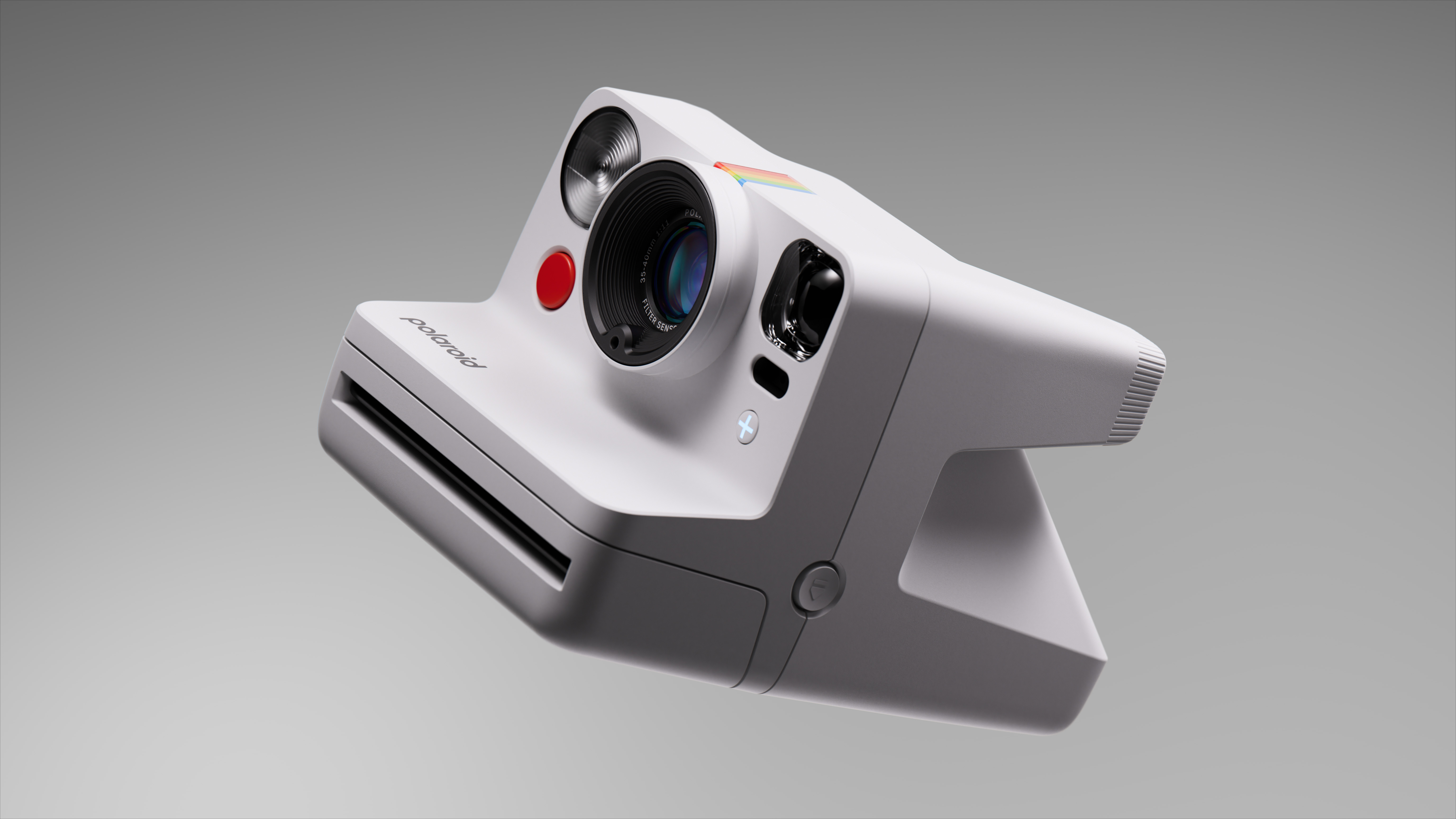 Kırmızı düğmeli, siyah lensli beyaz Polaroid anında fotoğraf makinesi, gri arka plan.