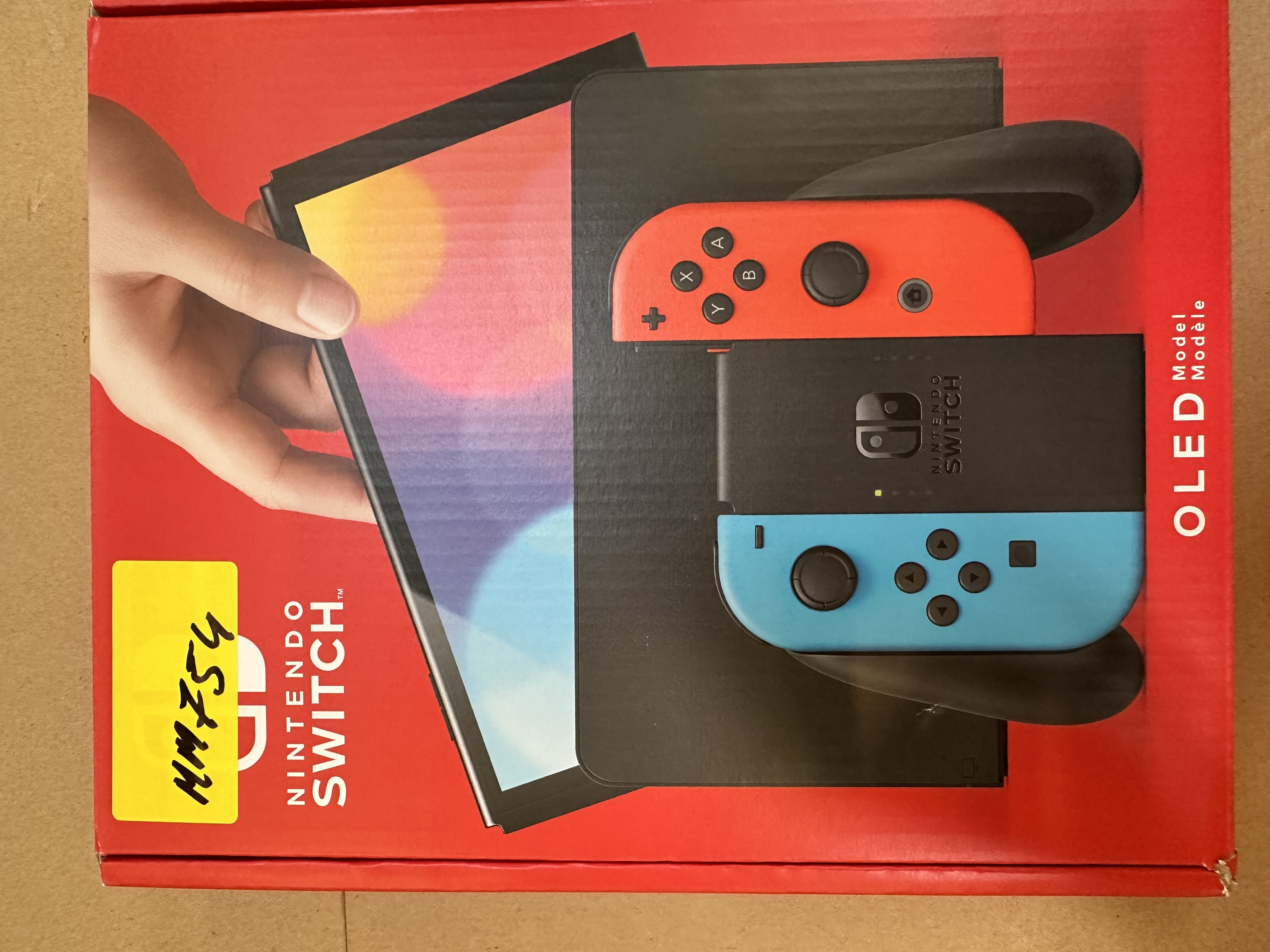 Otwarty karton Nintendo Switch, pokazujący konsolę i kontrolery. Czerwone i niebieskie kontrolery, czarna konsola.