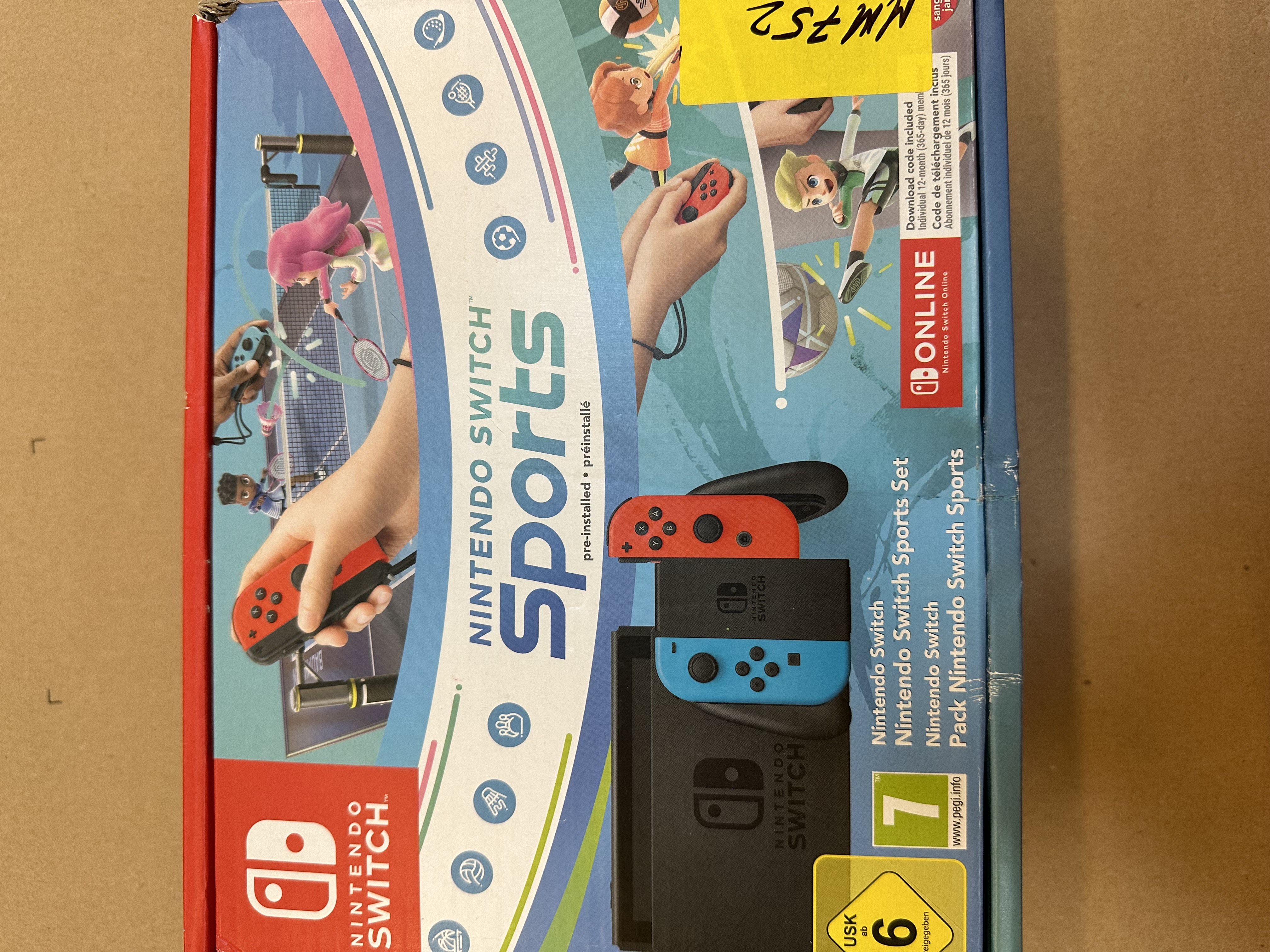 Pudełko z grą Nintendo Switch z czerwonymi i niebieskimi kontrolerami na brązowej powierzchni.