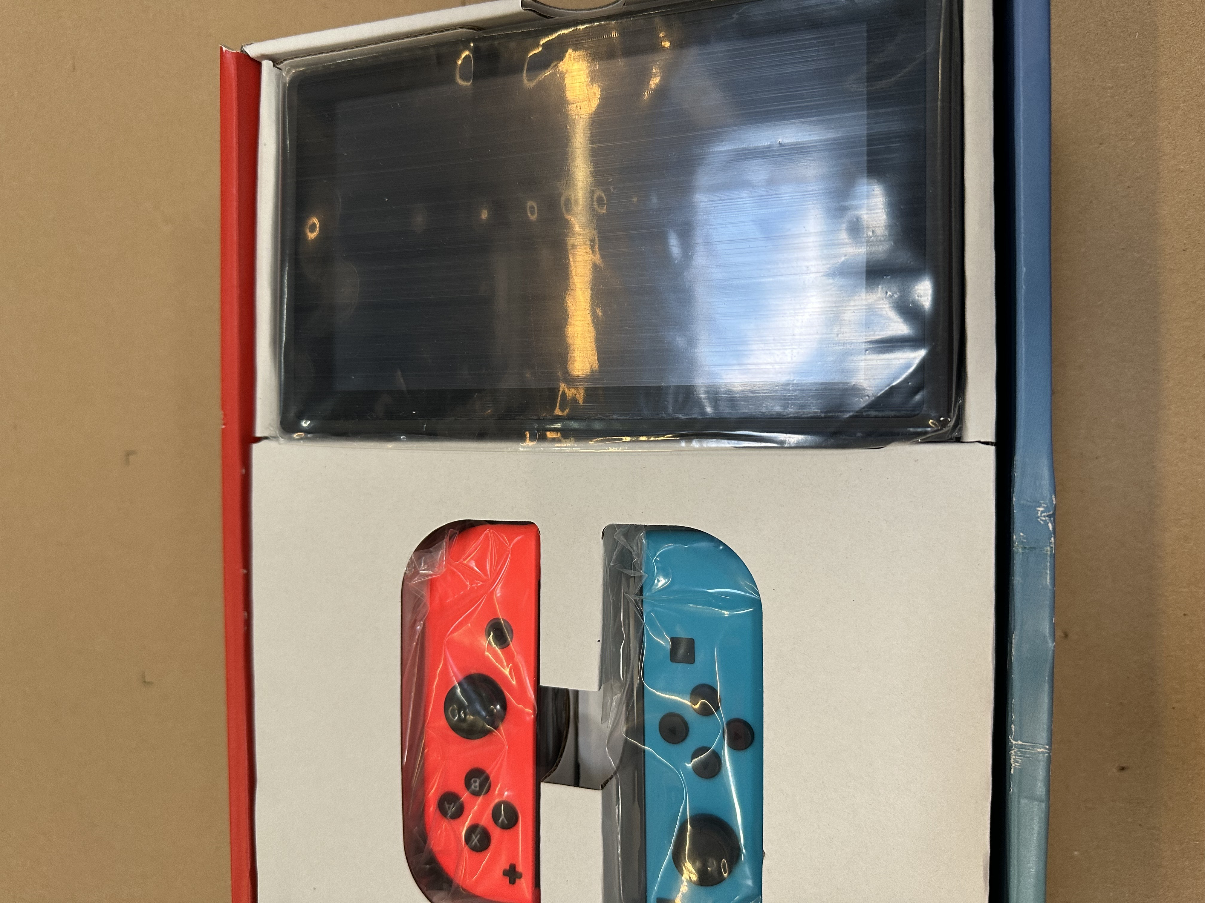 Kontrolery Nintendo Switch, czerwone i niebieskie, w opakowaniu.