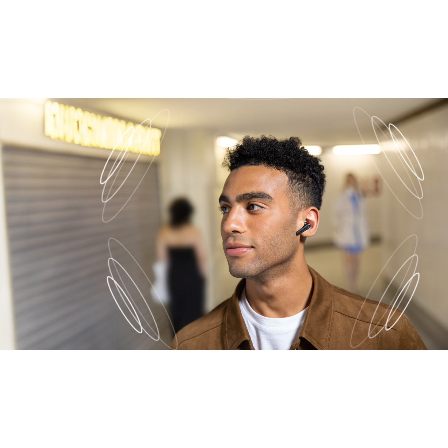 Man wearing earbuds in a subway tunnel. Sound waves emanate from the earbuds.