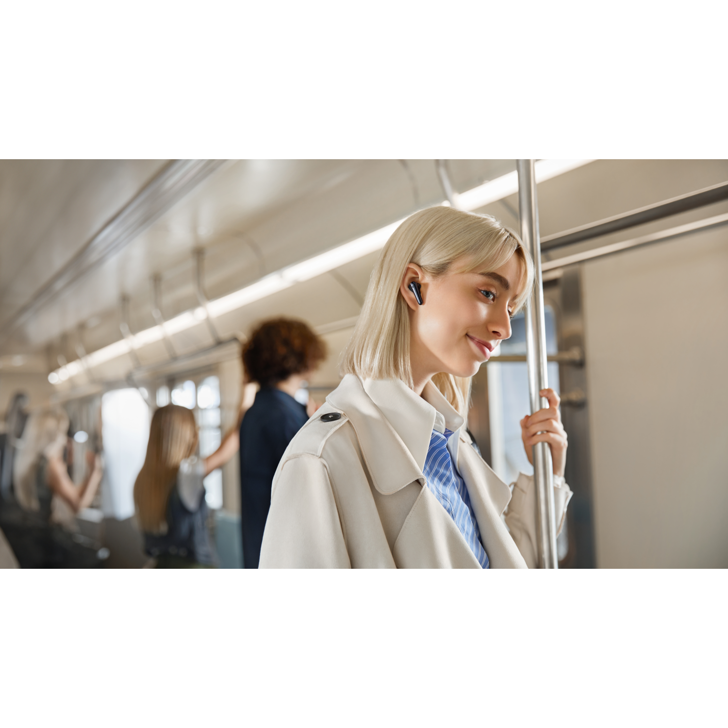 Vrouw met oortelefoons in een trein. Andere mensen op de achtergrond. Interieurfoto.