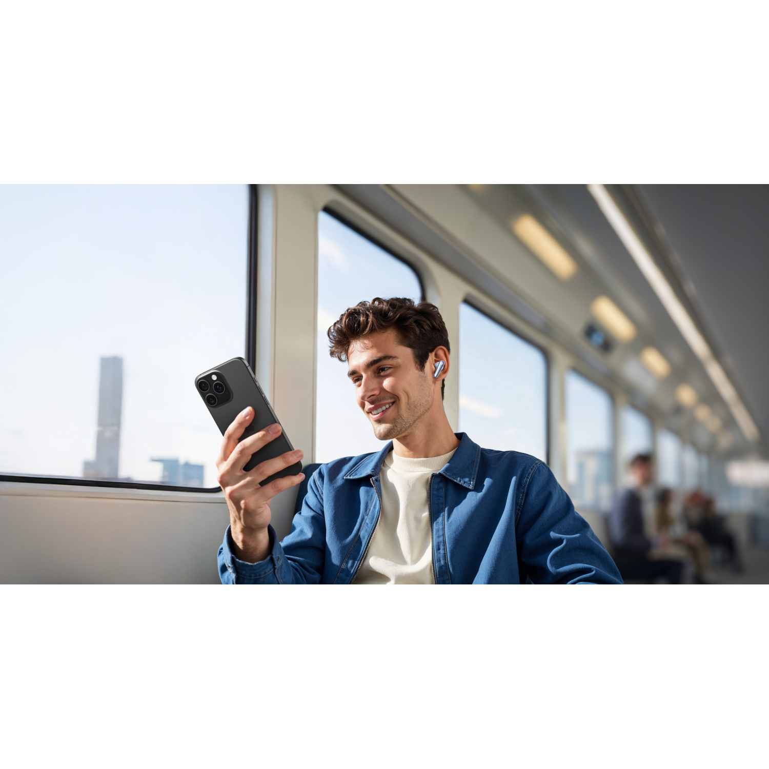 Man die een telefoon gebruikt, met oortelefoons, in een trein. De achtergrond is een stad.