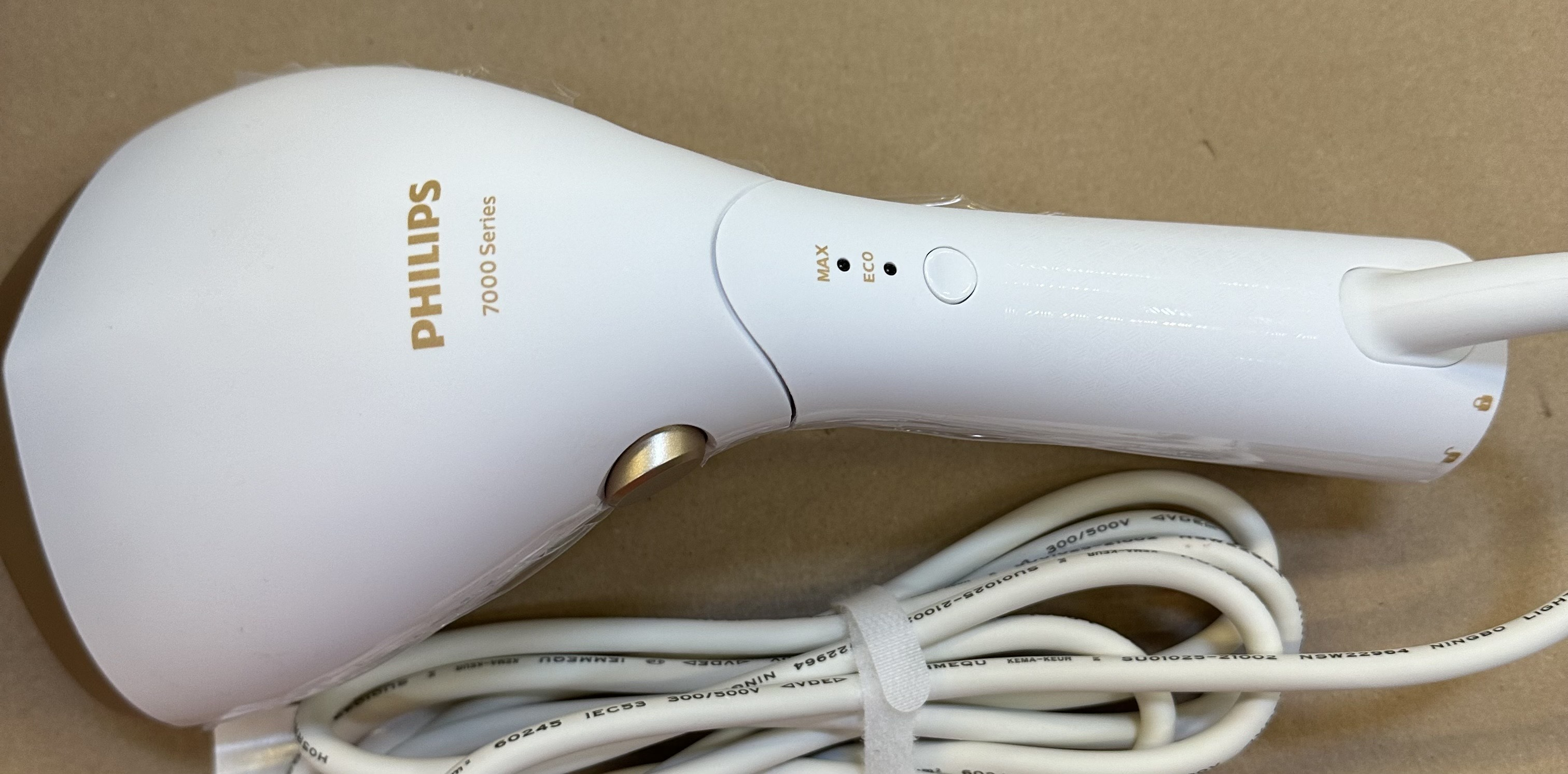 Biała parownica ręczna Philips serii 7000 i jej kabel elektryczny.