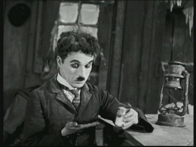 Charlie Chaplin in seiner Rolle, blickt auf etwas herab. Schwarz-Weiß-Bild.