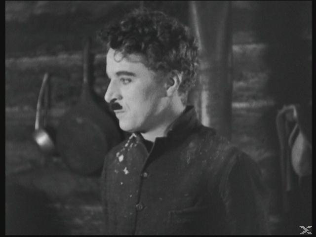 Chaplin mit Schnurrbart, der mit besorgtem Blick zur Seite schaut. Schwarz und Weiß.