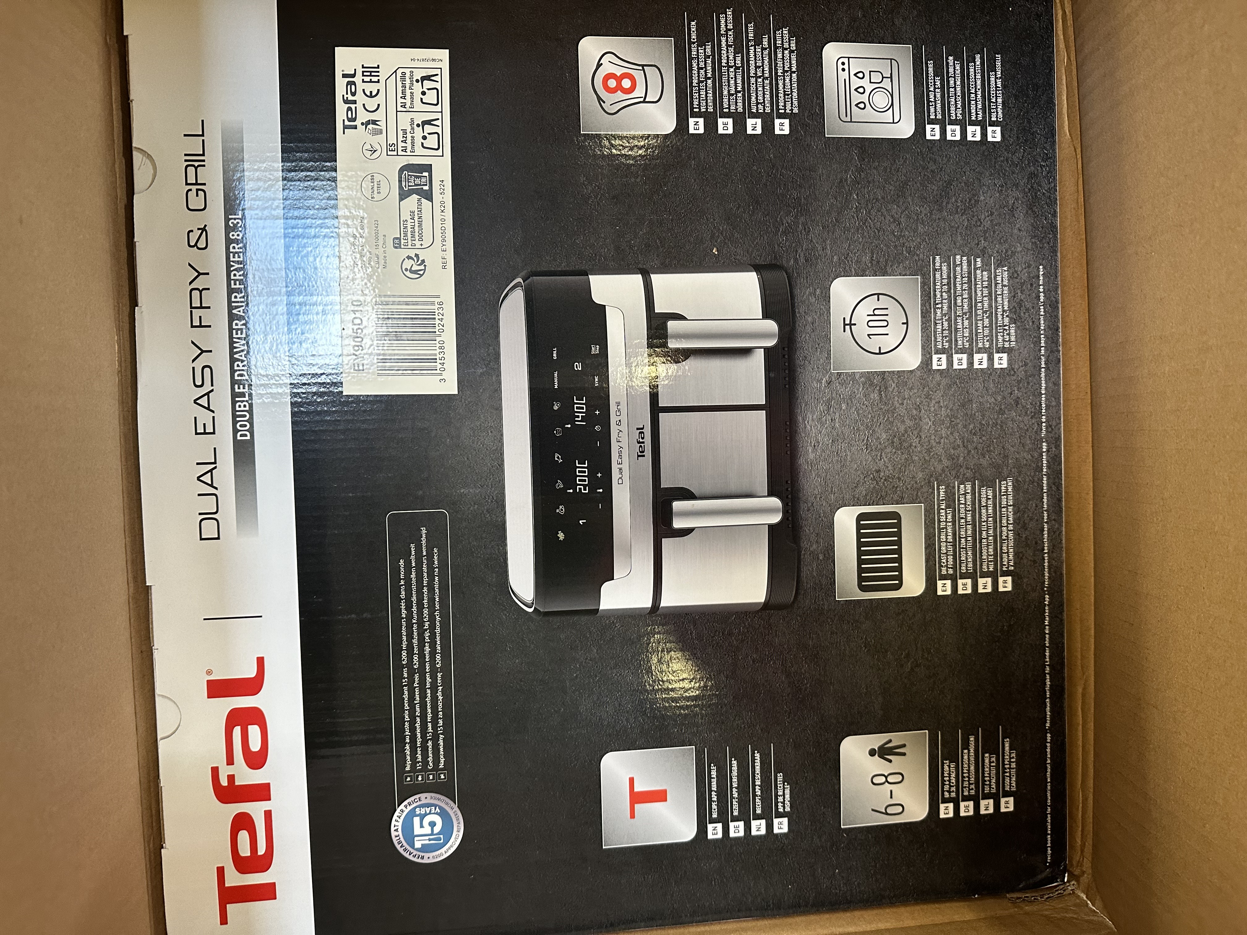 Frytownica beztłuszczowa w kartonie. Frytownica jest czarno-srebrna z cyfrowym wyświetlaczem.