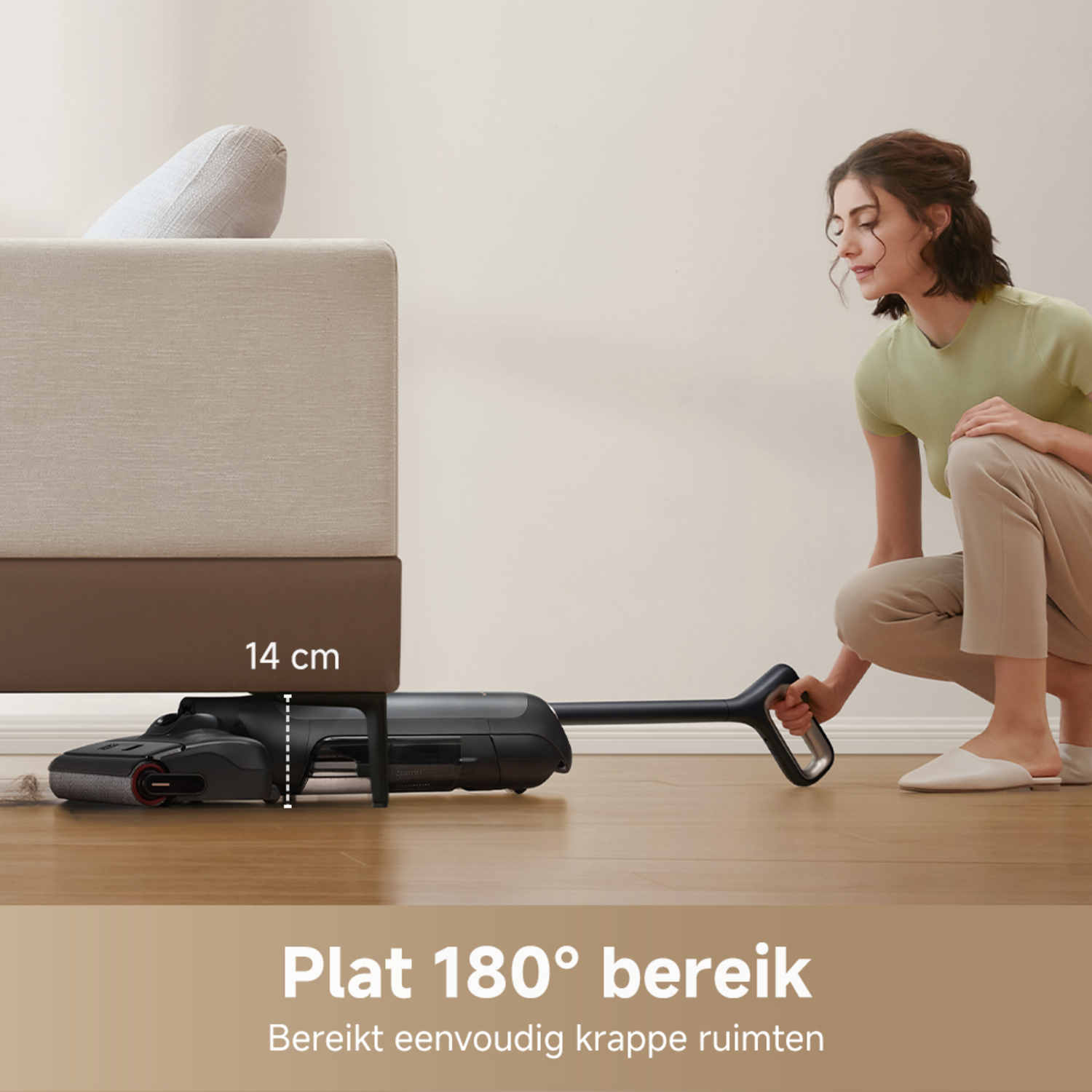 A woman using a vacuum cleaner under a sofa, reaching 180 degrees.