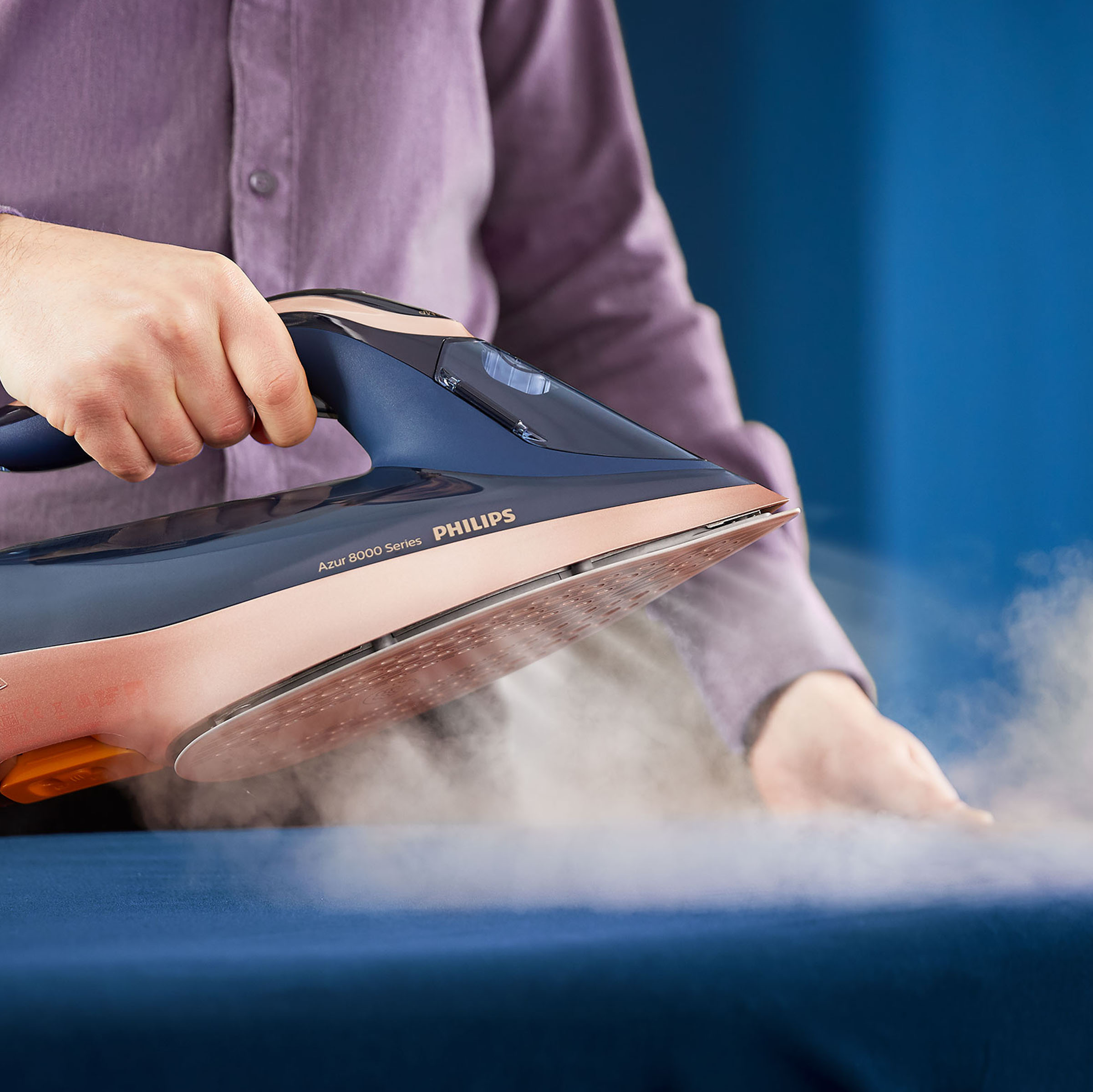 Osoba prasuje żelazkiem Philips Azur, widoczna para.