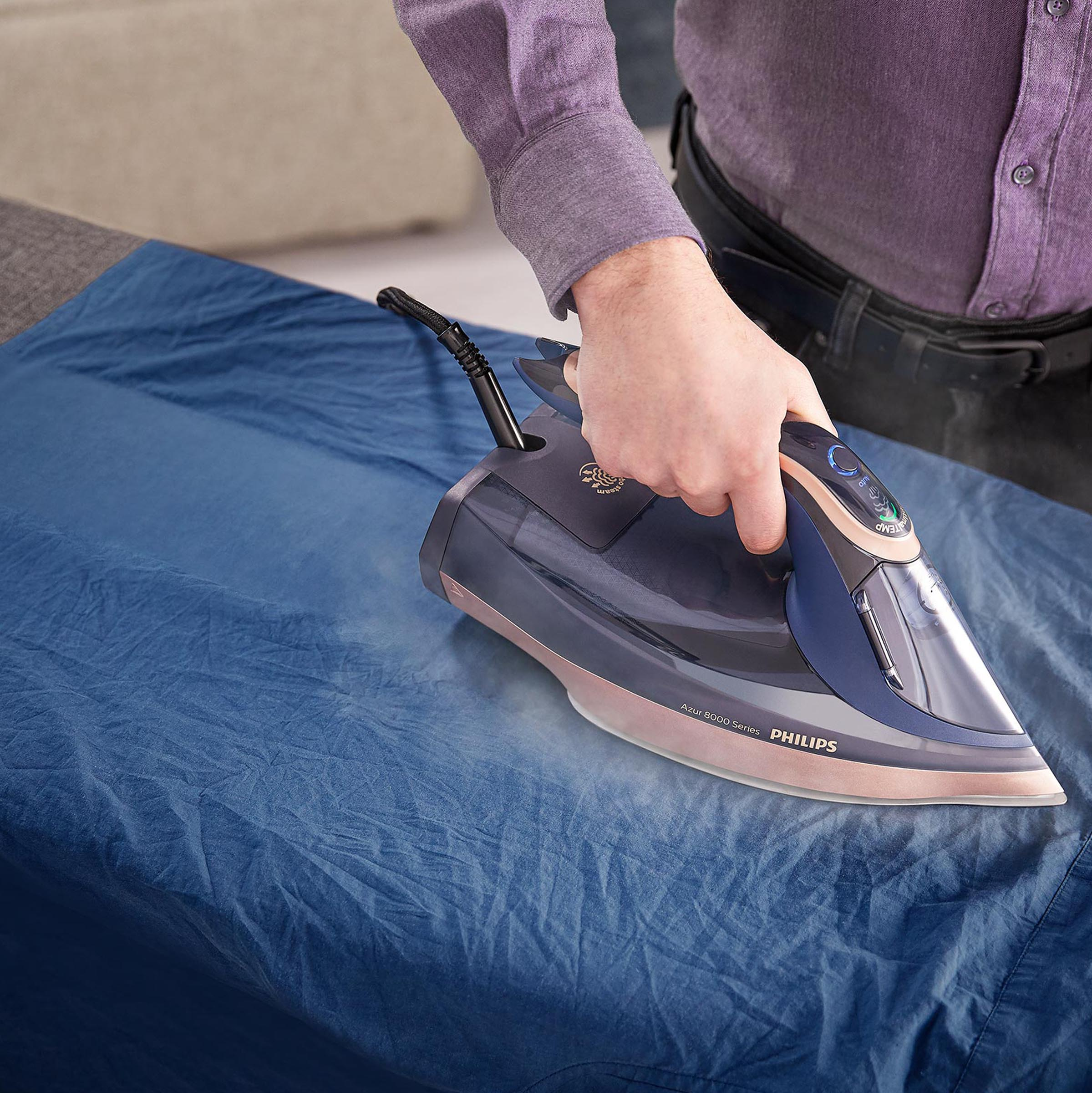 Osoba prasuje żelazkiem Philips Azur na niebieskiej tkaninie.