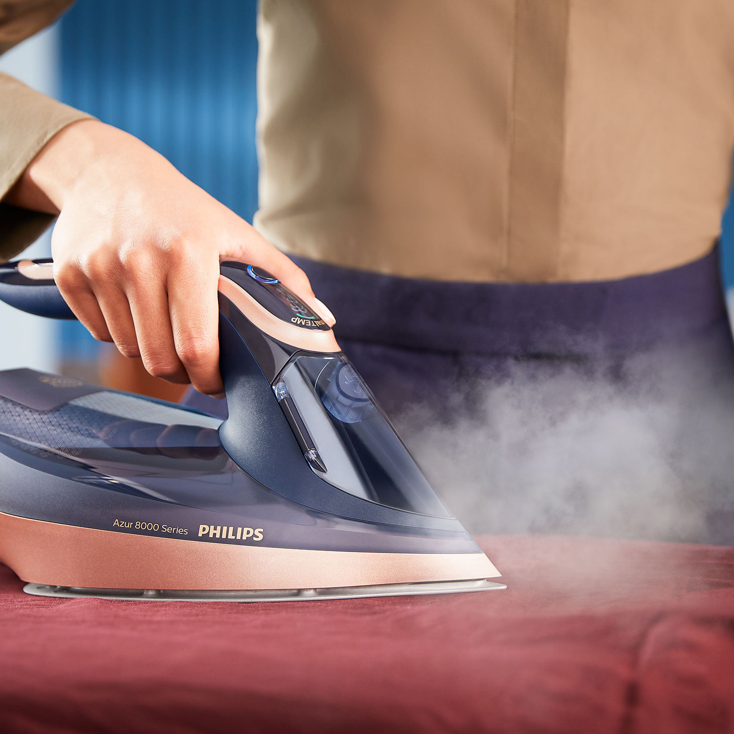 Osoba prasuje żelazkiem Philips Azur na czerwonej tkaninie.