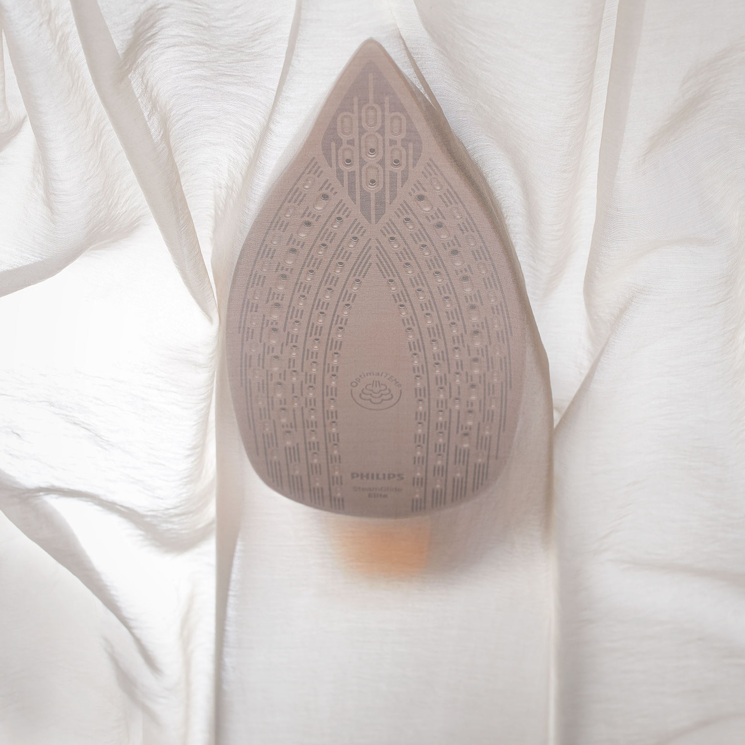 Zbliżenie stopy żelazka na białej tkaninie.